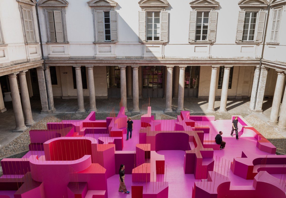 Lina Ghotmeh, Metamorphosis in Motion, 2026. Site-specific installation in the Cortile d'Onore of Palazzo Litta, Milan Design Week 2026. Pink curved labyrinthine pavilion transforming the Baroque courtyard.