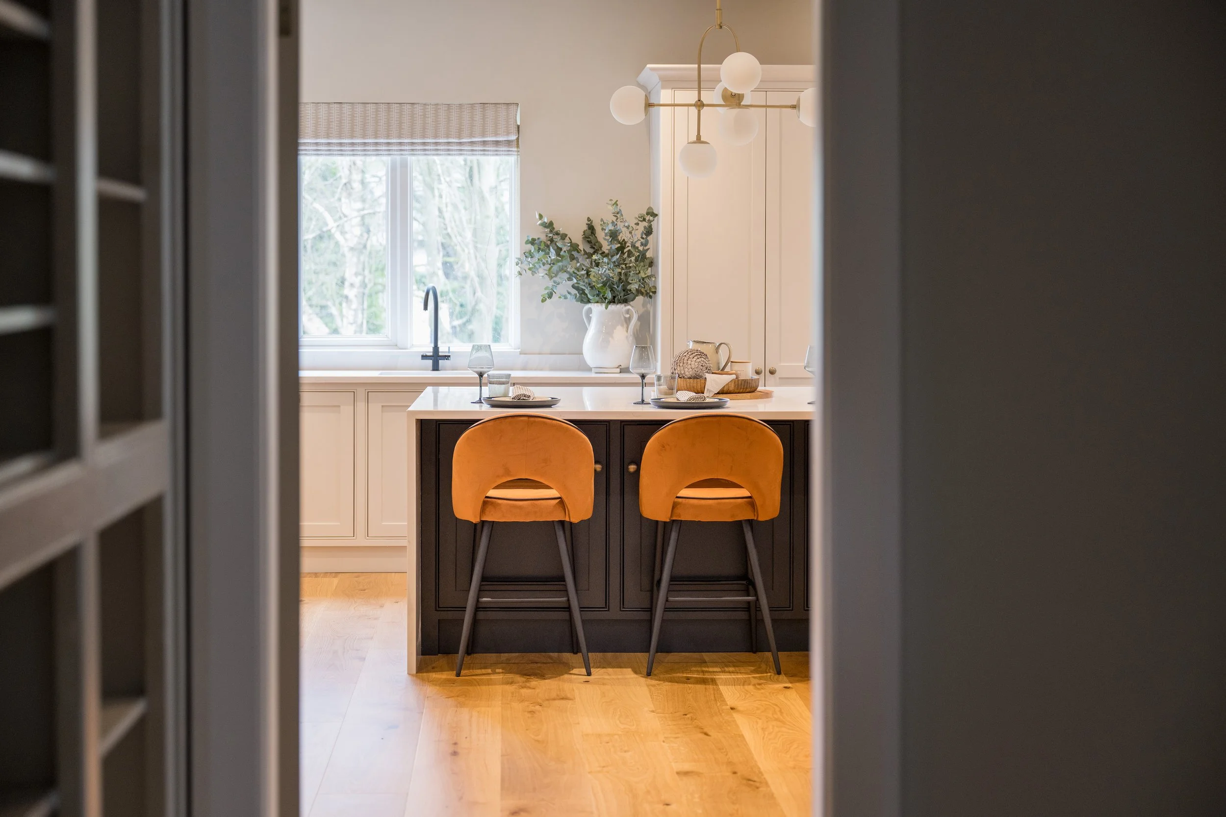 Bespoke kitchen designed by StyleSmith Interiors featuring a painted island, mustard velvet bar stools and timeless cabinetry in a Harrogate home
