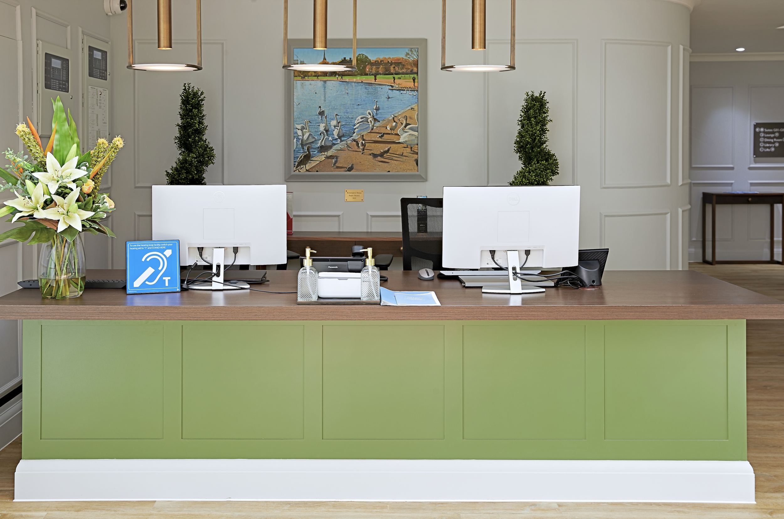 Contemporary care home reception designed by StyleSmith Interiors featuring bespoke green joinery, accessible reception desk and welcoming entrance