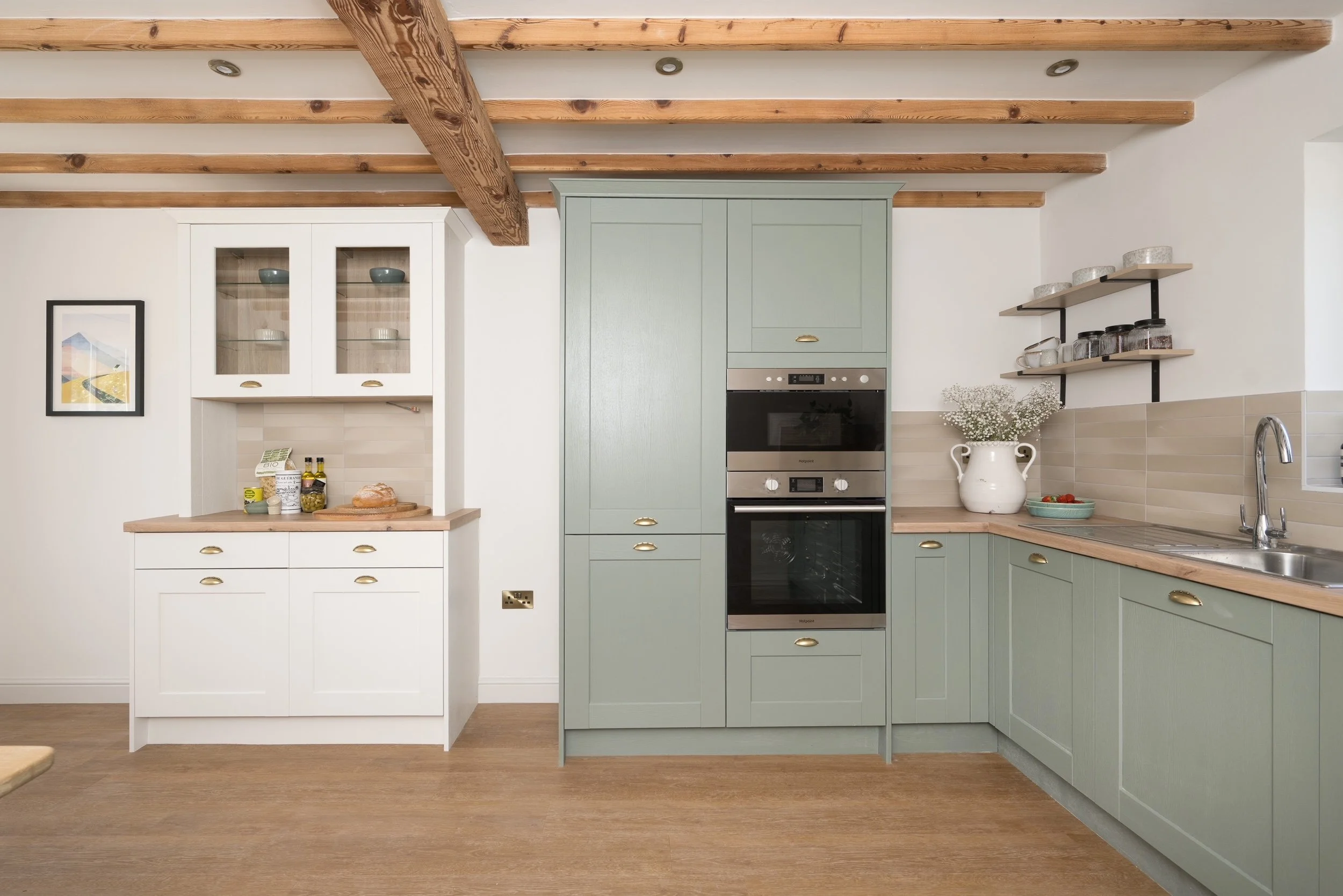 Country-style shaker kitchen designed by StyleSmith Interiors featuring sage green cabinetry, exposed timber beams and bespoke joinery
