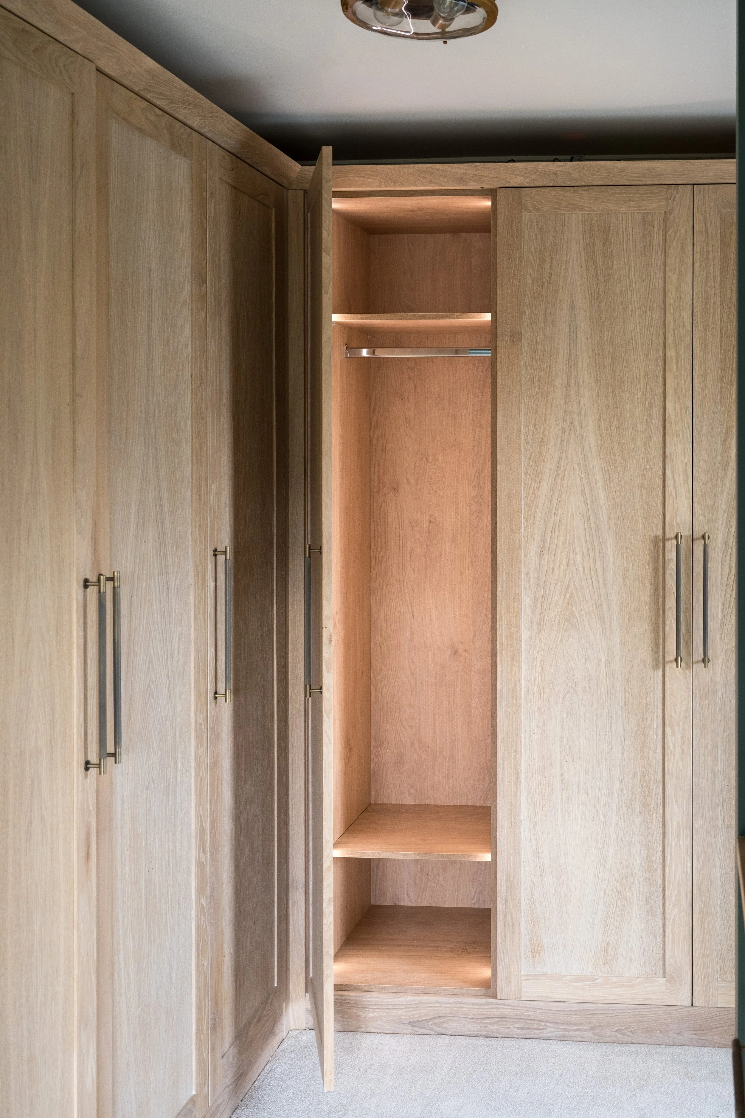 Bespoke oak fitted wardrobes with integrated lighting and handcrafted storage designed by StyleSmith Interiors Harrogate Interior Design Studio