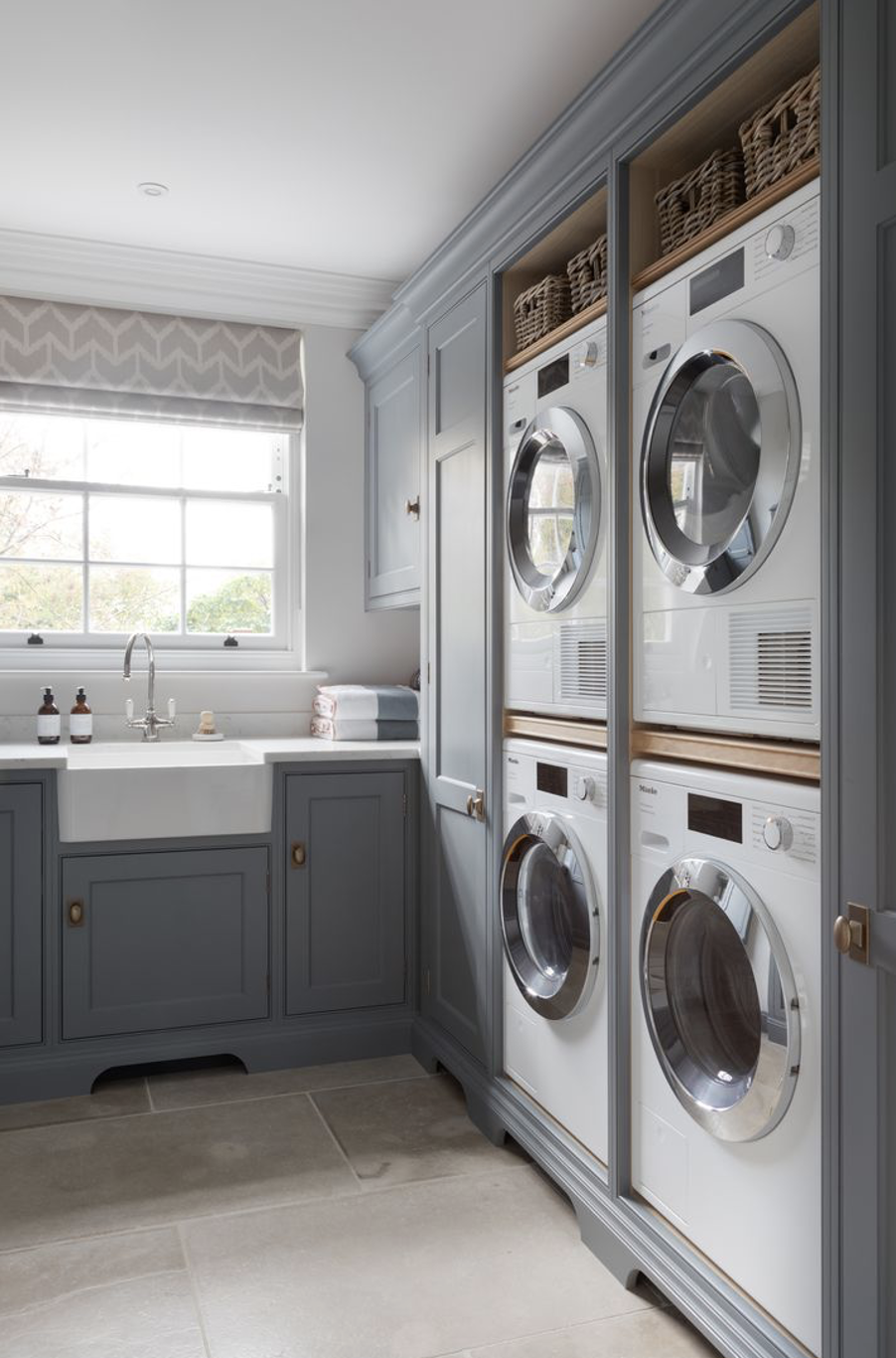 Bespoke utility room with shaker cabinets, stacked washing machines, Belfast sink and custom storage by StyleSmith Interiors, Harrogate interior designers