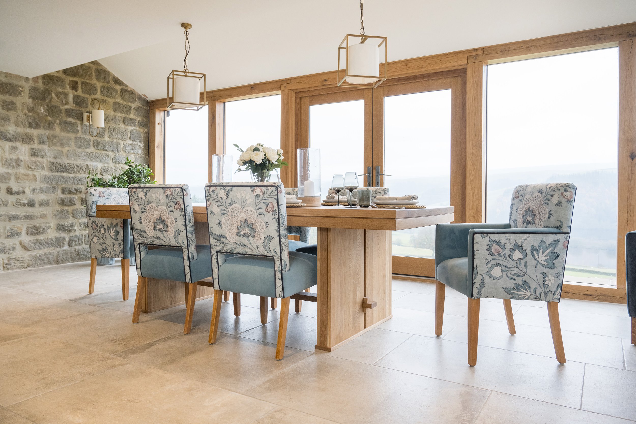 Modern dining room with oak dining table, patterned upholstered chairs and floor-to-ceiling glazing by StyleSmith Interiors, Harrogate interior designers