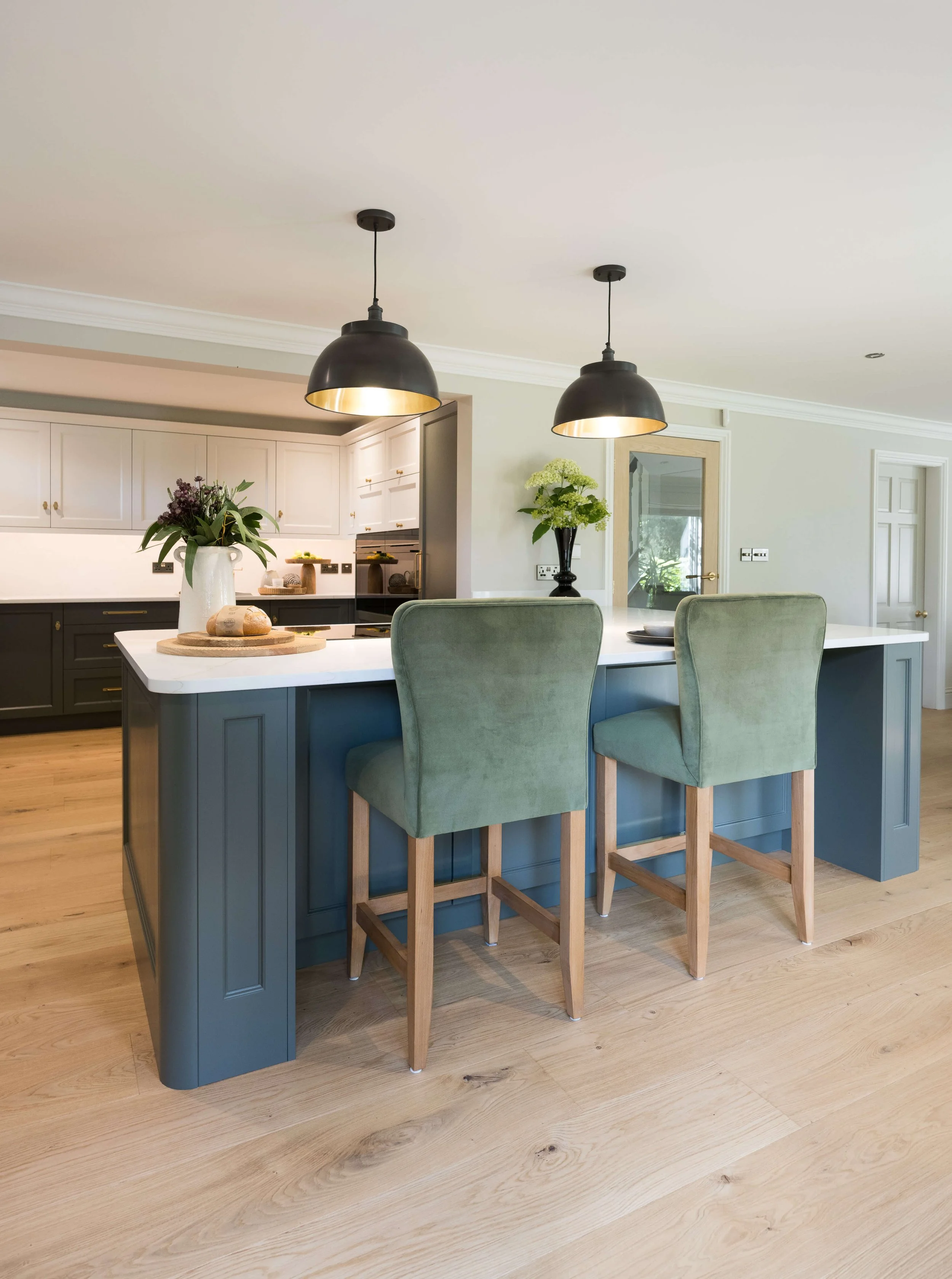 Luxury kitchen by StyleSmith Interiors featuring a painted blue island, upholstered bar stools and statement pendant lighting
