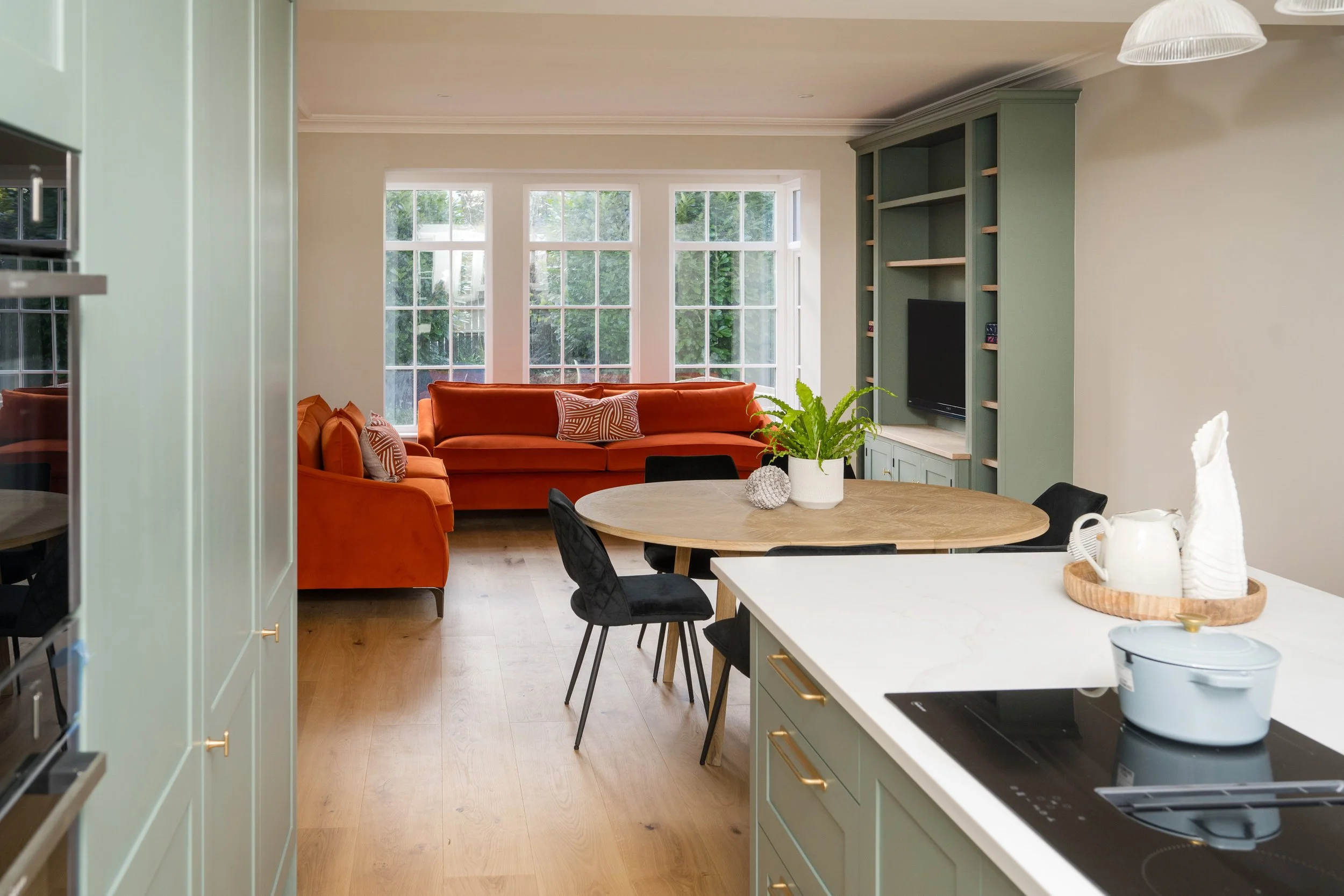 Open-plan kitchen and living room designed by StyleSmith Interiors featuring an orange sofa, large windows and modern family-friendly interior in Yorkshire