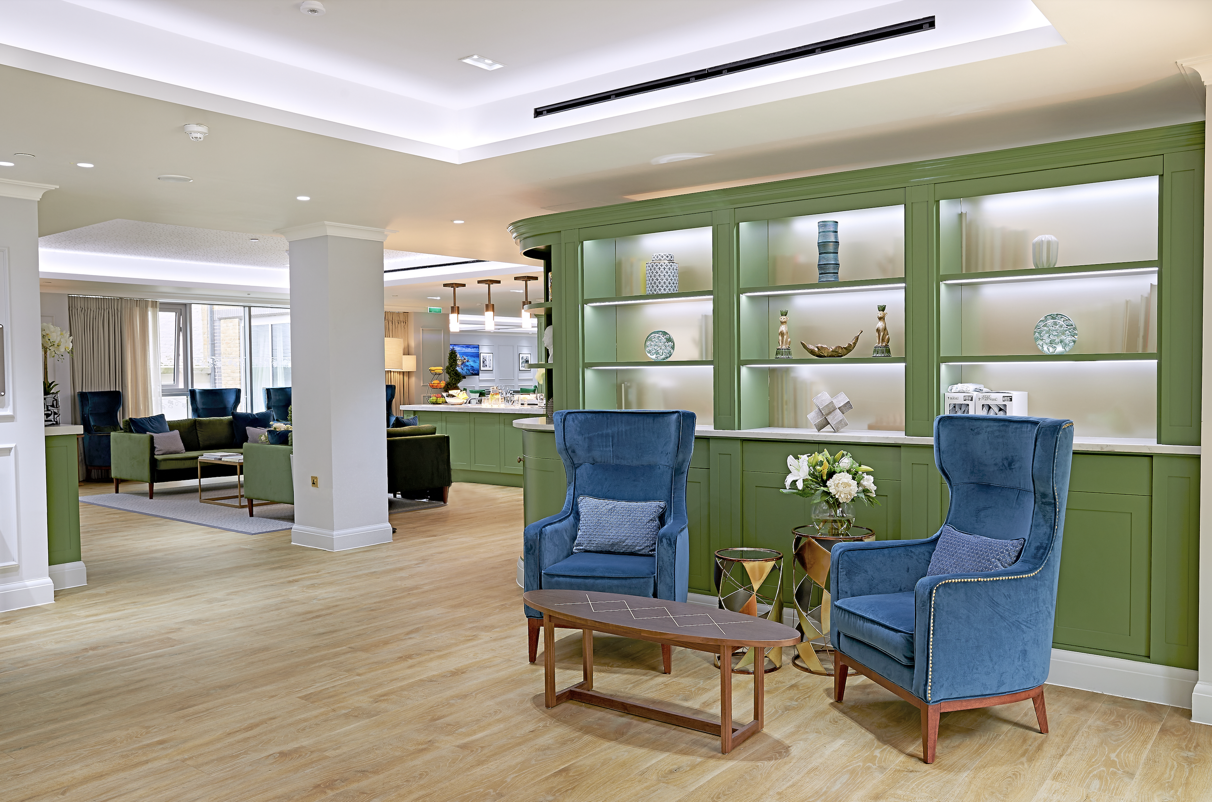 Elegant communal lounge for a senior living residence featuring bespoke illuminated cabinetry, comfortable seating and contemporary interior design by StyleSmith Interiors