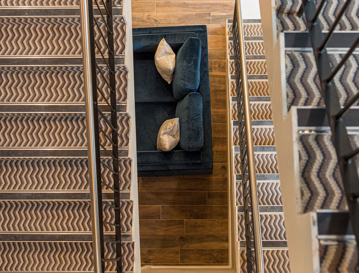 Harrogate interior designer StyleSmith Interiors staircase with patterned carpet, black couch with beige pillows, and wooden flooring in modern home.