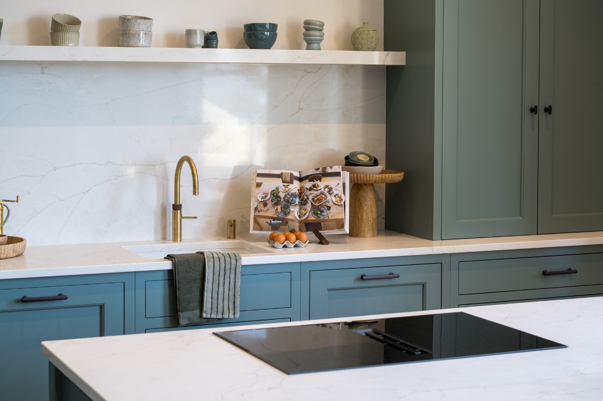 Bespoke kitchen designed by StyleSmith Interiors featuring blue shaker cabinetry, quartz worktops, brass tap and carefully styled accessories in Harrogate