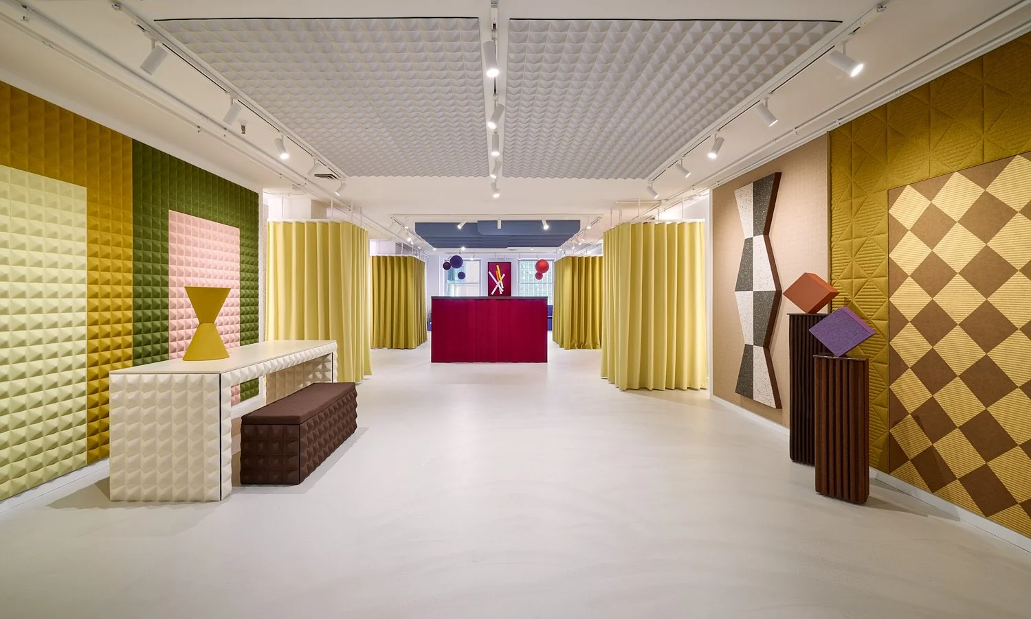 Chicago Showroom of Slalom Acoustics in The Mart, with colorful geometric and textured wall panels, display tables, and acoustic curtains, leading to more acoustic solutions in the back