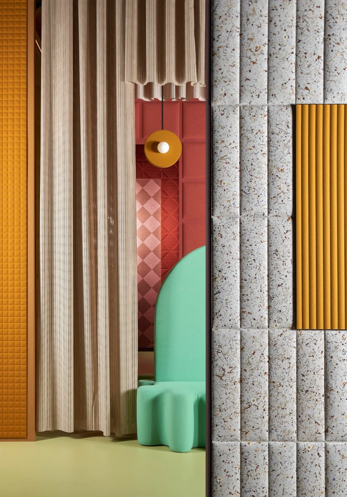 Showroom space of Slalom Acoustics with colorful acoustic wall panels, acoustic beige curtains, a green upholstered chair as shown during Milan Design Week, Salone di Mobile 2026