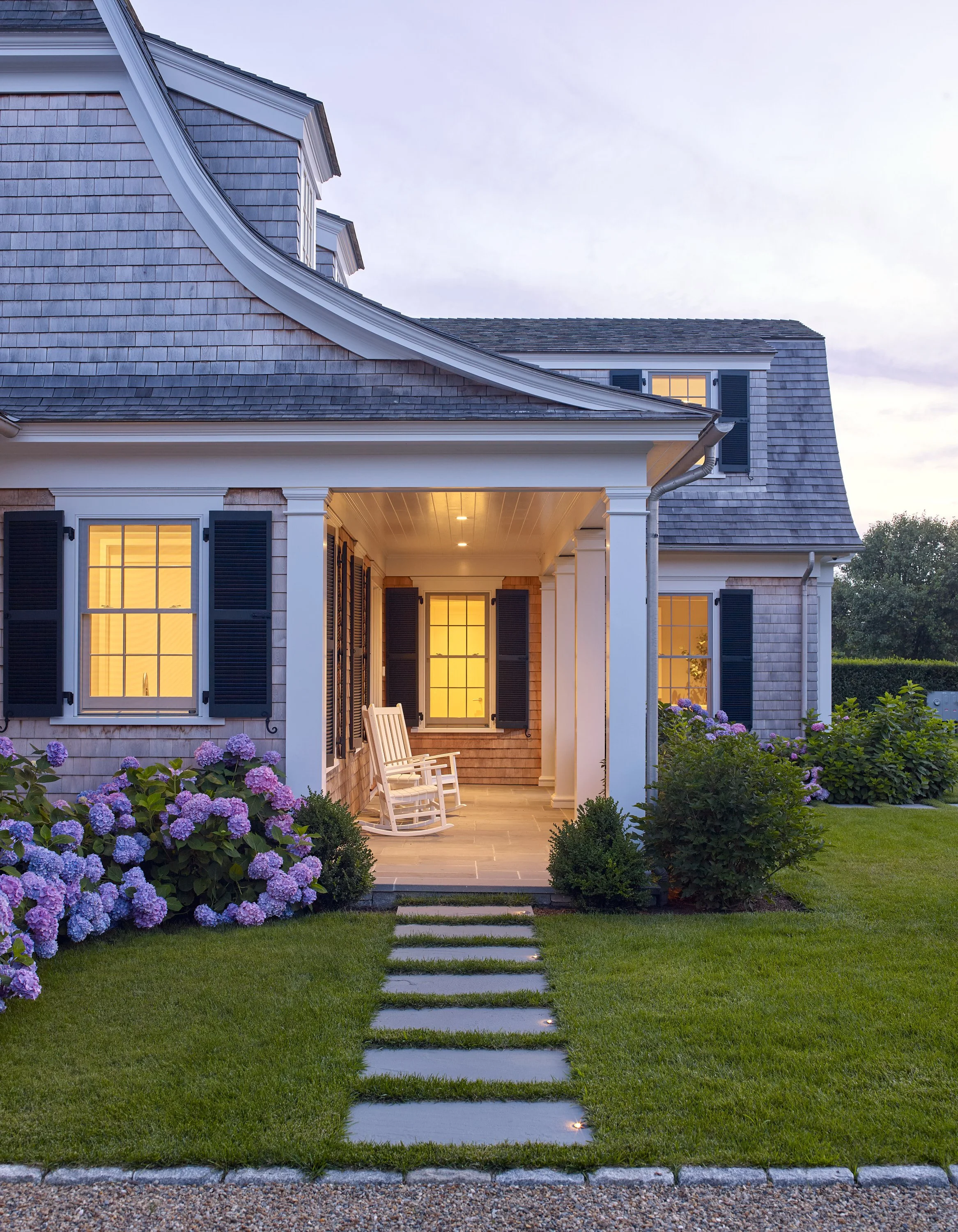 Traditional shingle style home view of porch, walkway, hydrangeas, and landscaping lighting on Martha's Vineyard.