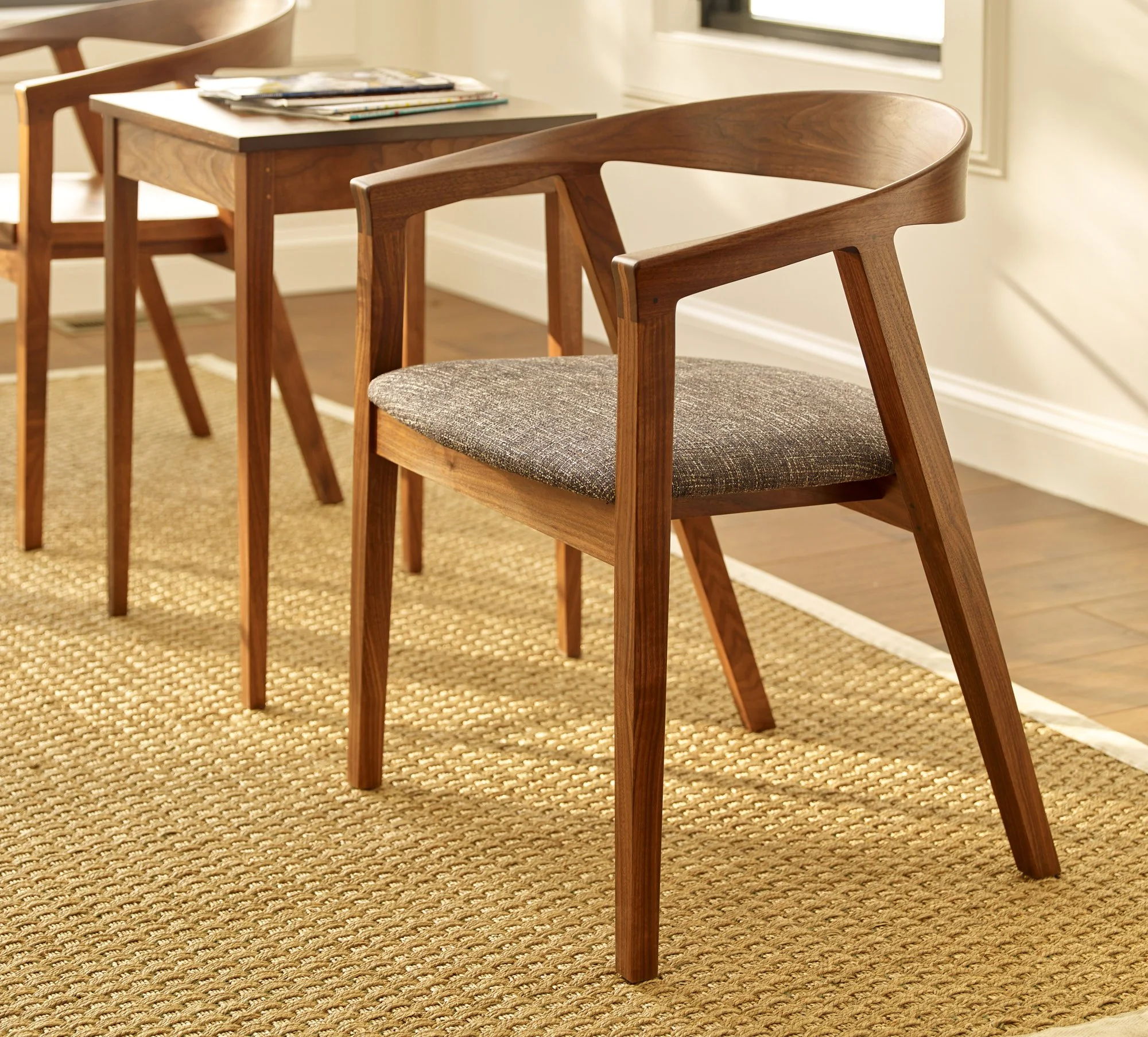 Wooden dining chairs around a wooden table in a bright room with a window.