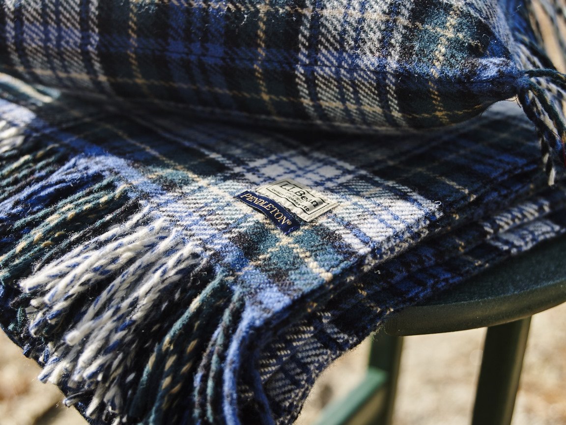 Close-up of a folded Pendleton plaid blanket with fringed edges, showing a fabric tag that reads "La Belle".