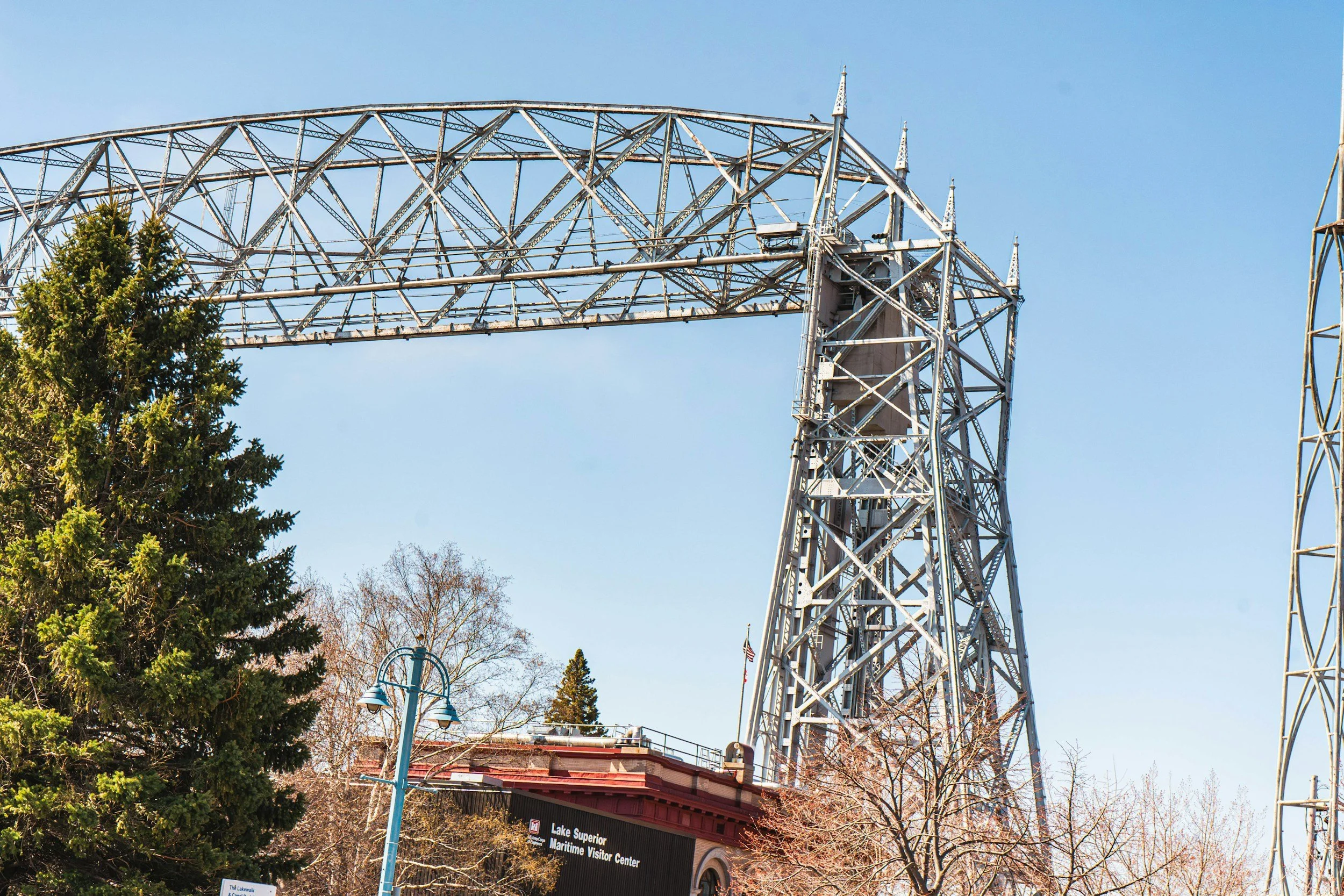 Steel roller coaster structure with trees and a sign for Lake Superior Maritime Visitor Center in the foreground.
