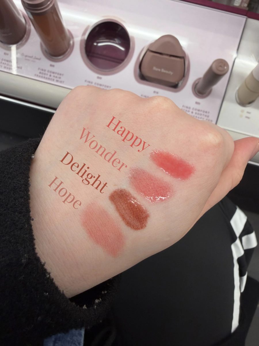 Swatches of the Rare Beauty Soft Pinch Lip Oil Tint. The featured shades are "Happy" (cool pink), "Wonder" (rose mauve), "Delight" (rose brown), and "Hope" (nude mauve).