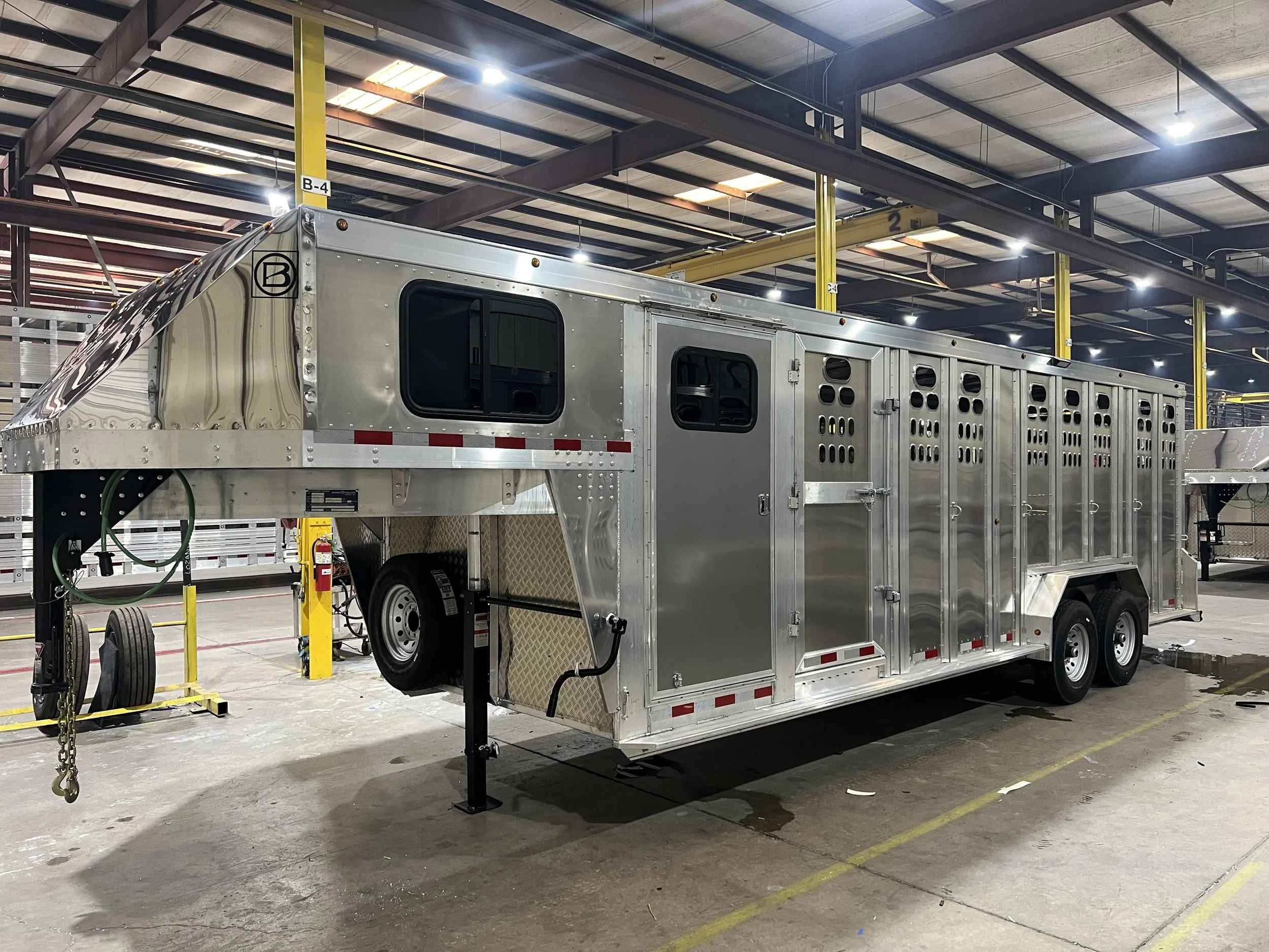 Custom aluminum gooseneck cattle trailer built by Barrett Trailers inside the manufacturing facility