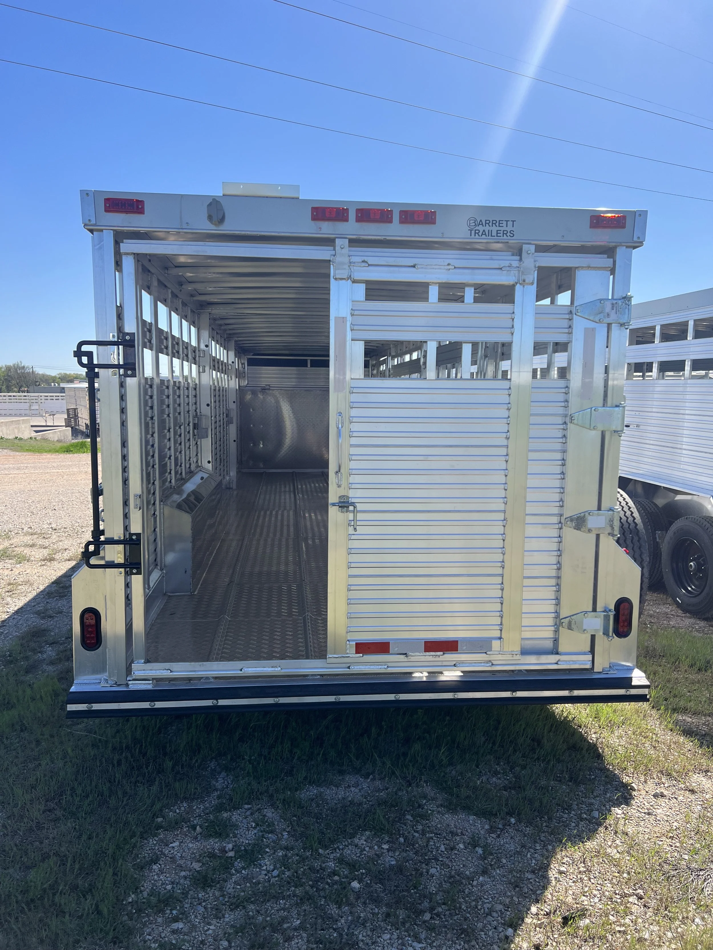 Rear view of a custom Barrett gooseneck cattle trailer with livestock loading gate