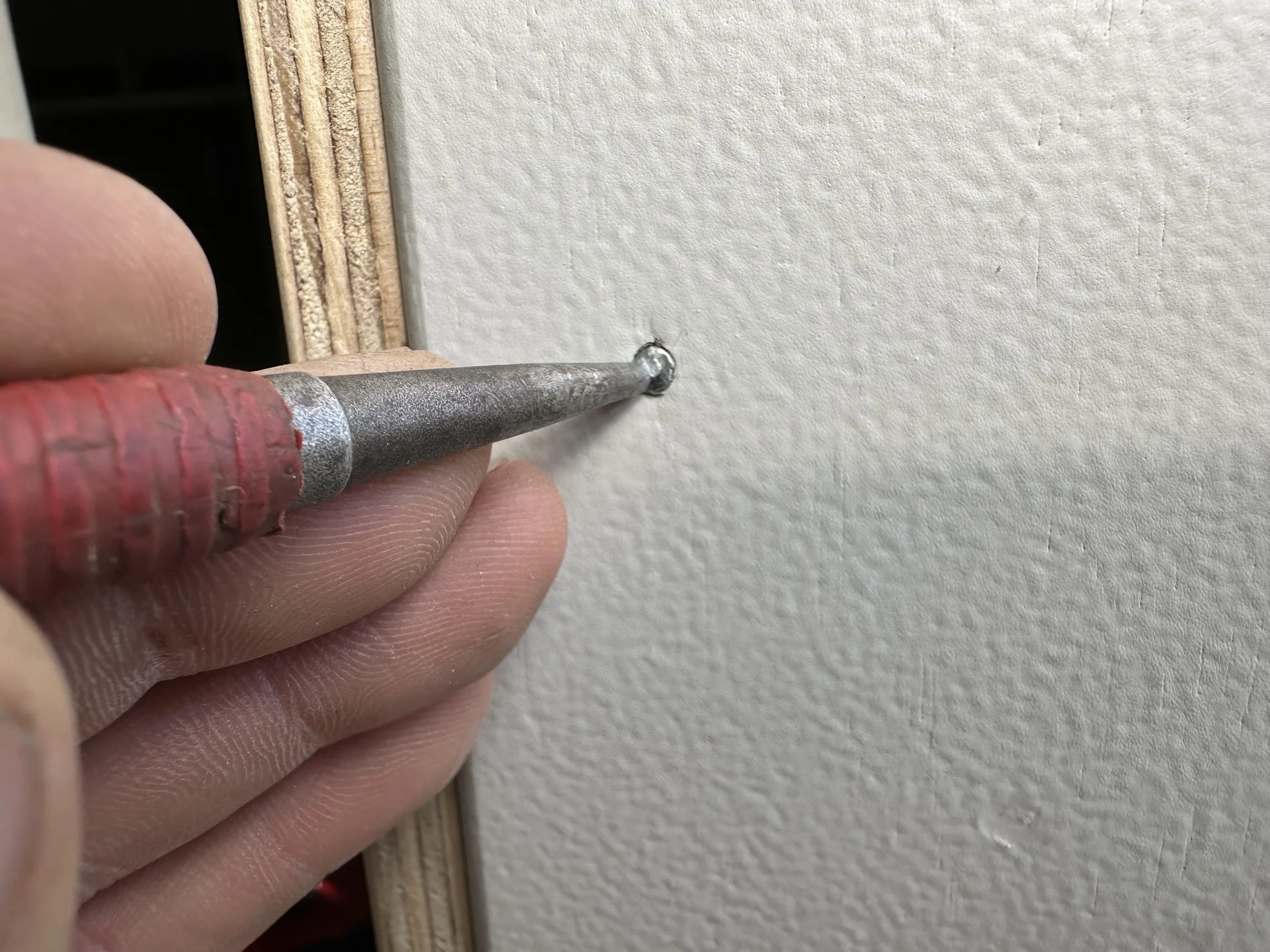 Finishing nails punched below the surface of the new garage door jamb ready for final finishing