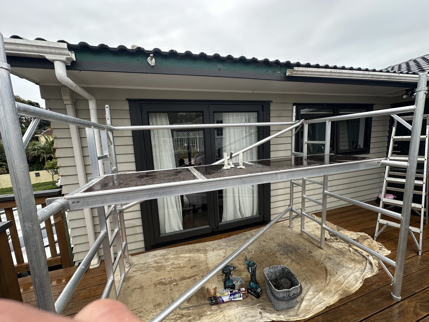 Mobile scaffold positioned for removal of gutter section during repair in Pakuranga