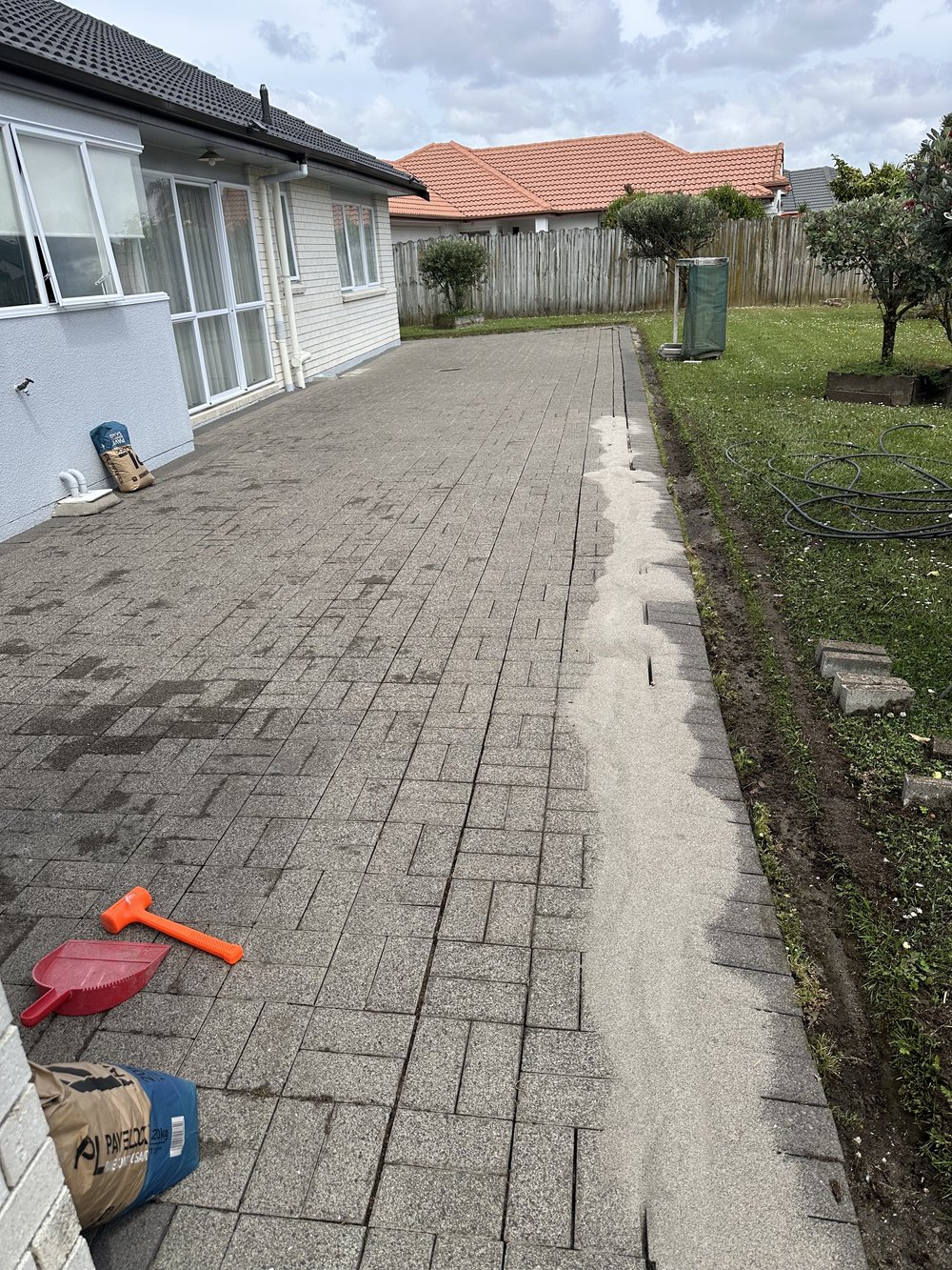 Brushing paving jointing sand into gaps across a large paved area in Golflands