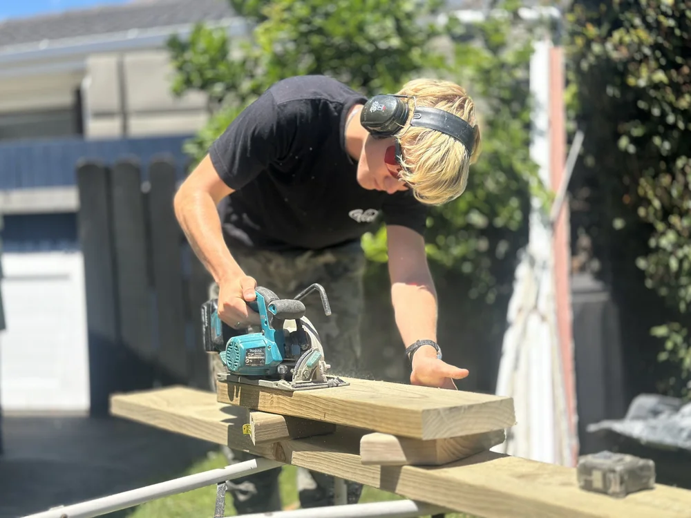 Ravil helping cut timber during a garden gate build in Shelly Park