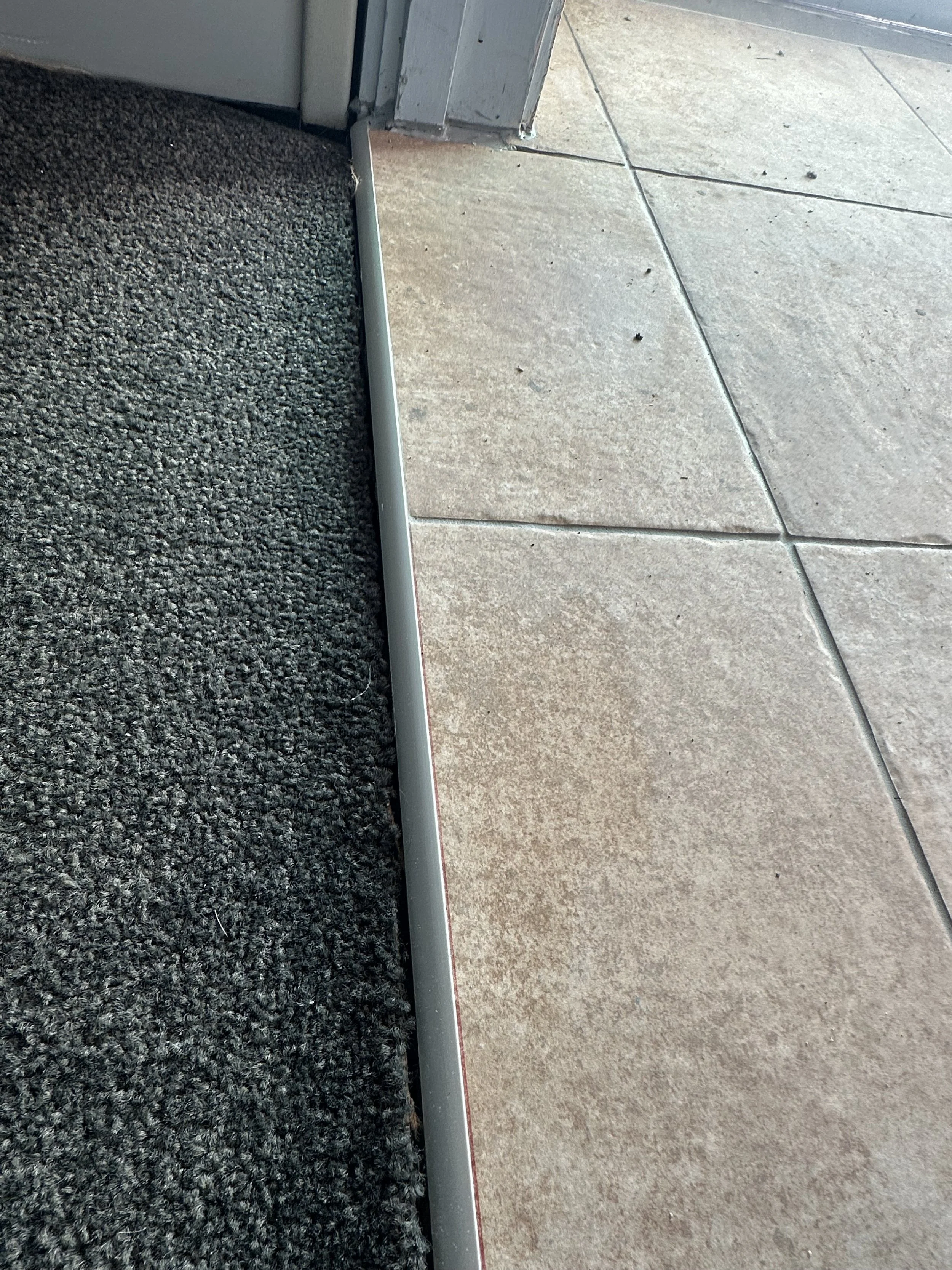 Stainless steel protective transition trim installed at a lift entrance to prevent future tile damage and improve durability in Auckland.