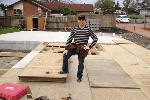 Rinat on site in 2014 during his early carpentry apprenticeship at Arctic Limited, standing on newly laid subfloor flooring over a new-build foundation in Auckland