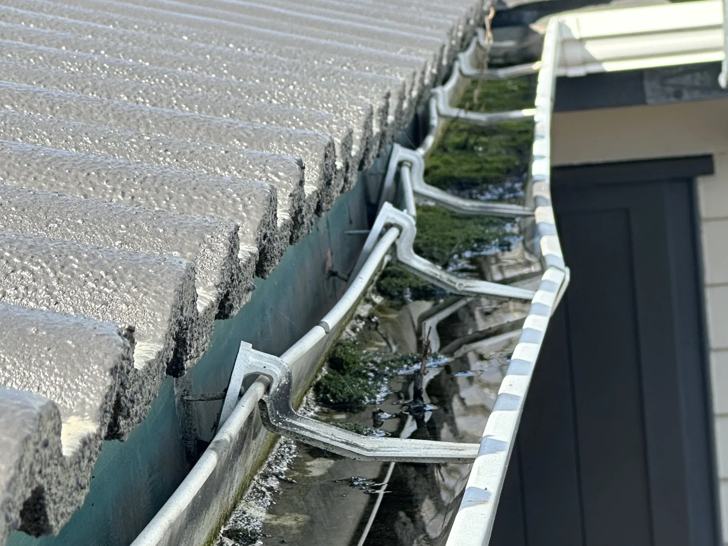 Gutter heavily blocked with wet roof debris before repair in Pakuranga