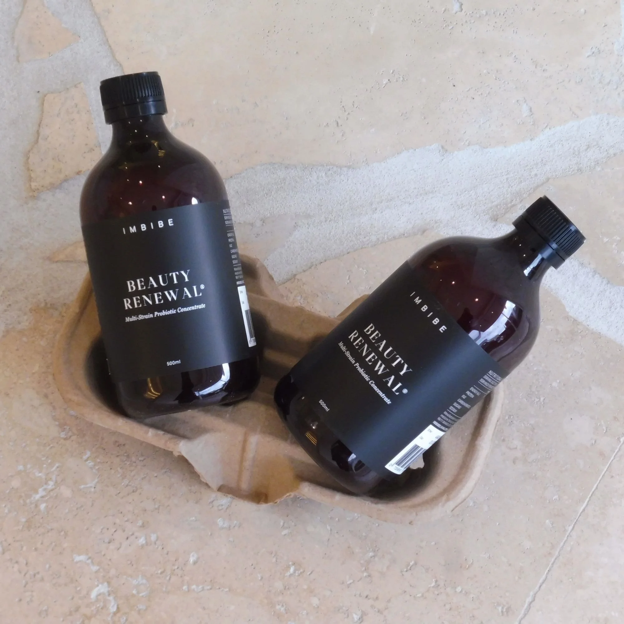 two bottles of IMBIBE beauty renewal probiotic concentrate designed to heal your gut health. Placed in a cardboard drink tray.