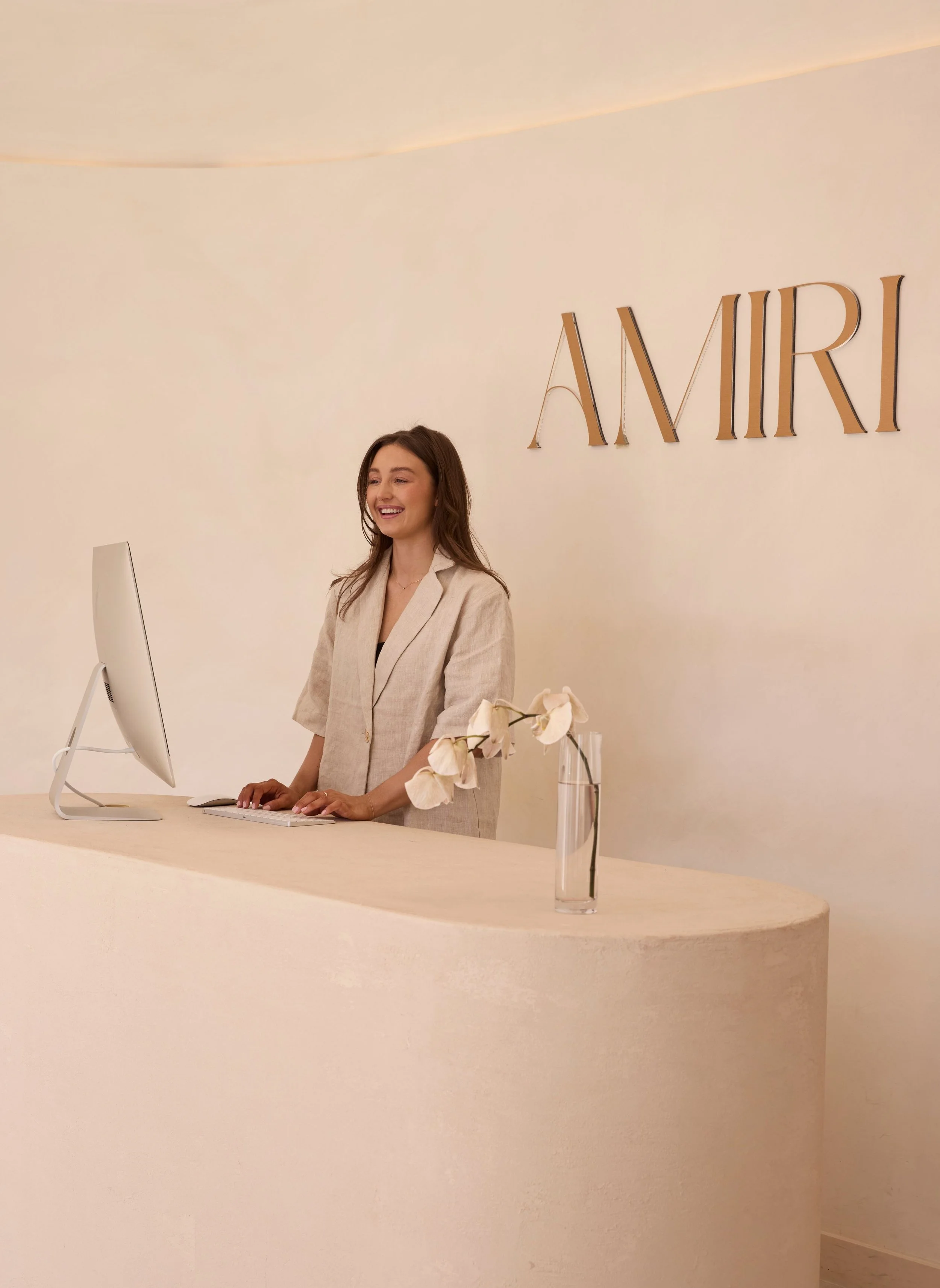 Founder Caitlin Hingst at the reception desk of AMIRI Studio in Newcastle to greet clients.
