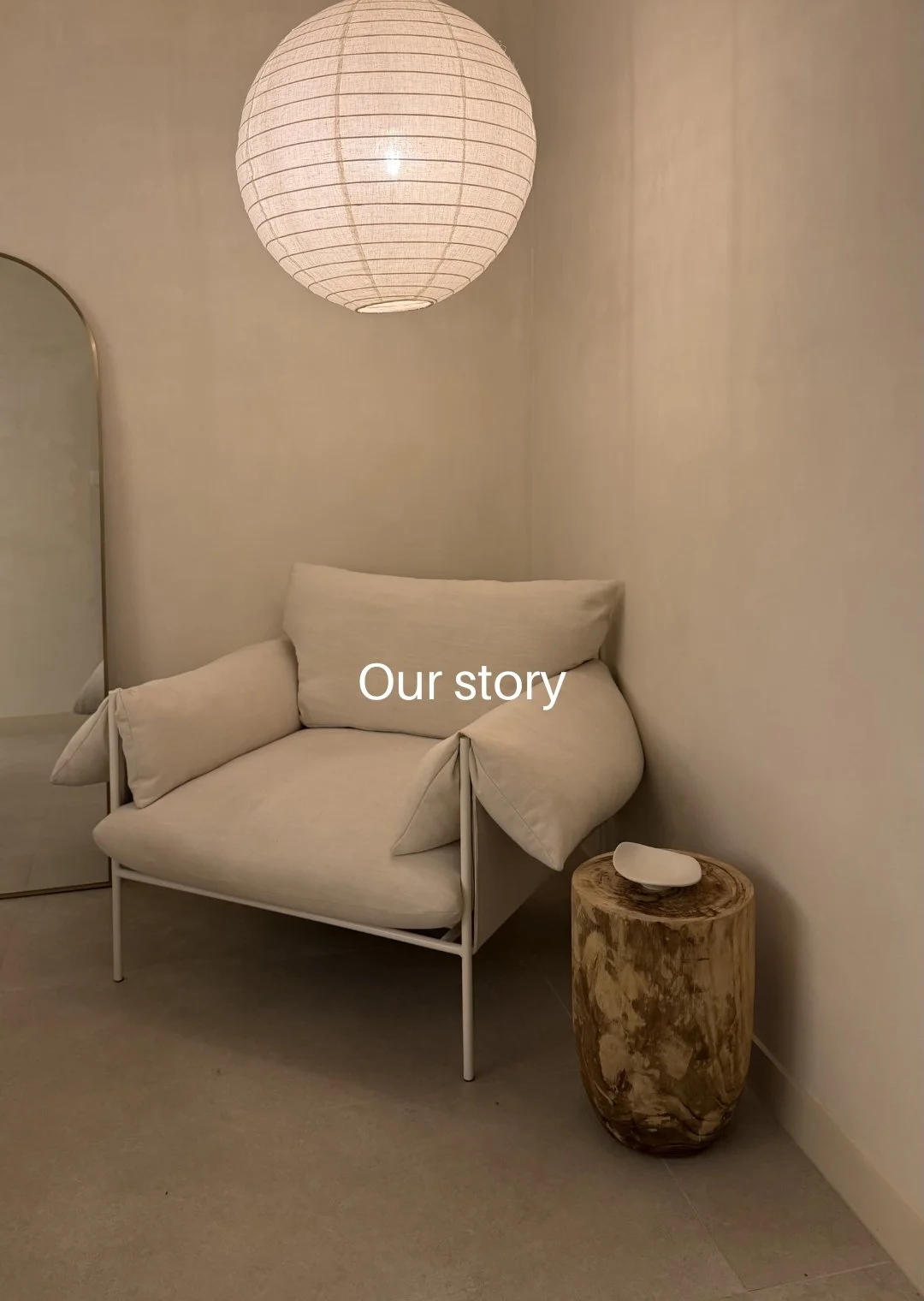 A big armchair with a wooden side table and linen lantern above in the Amiri Studio facial room for clients to enjoy in the newcastle studio.
