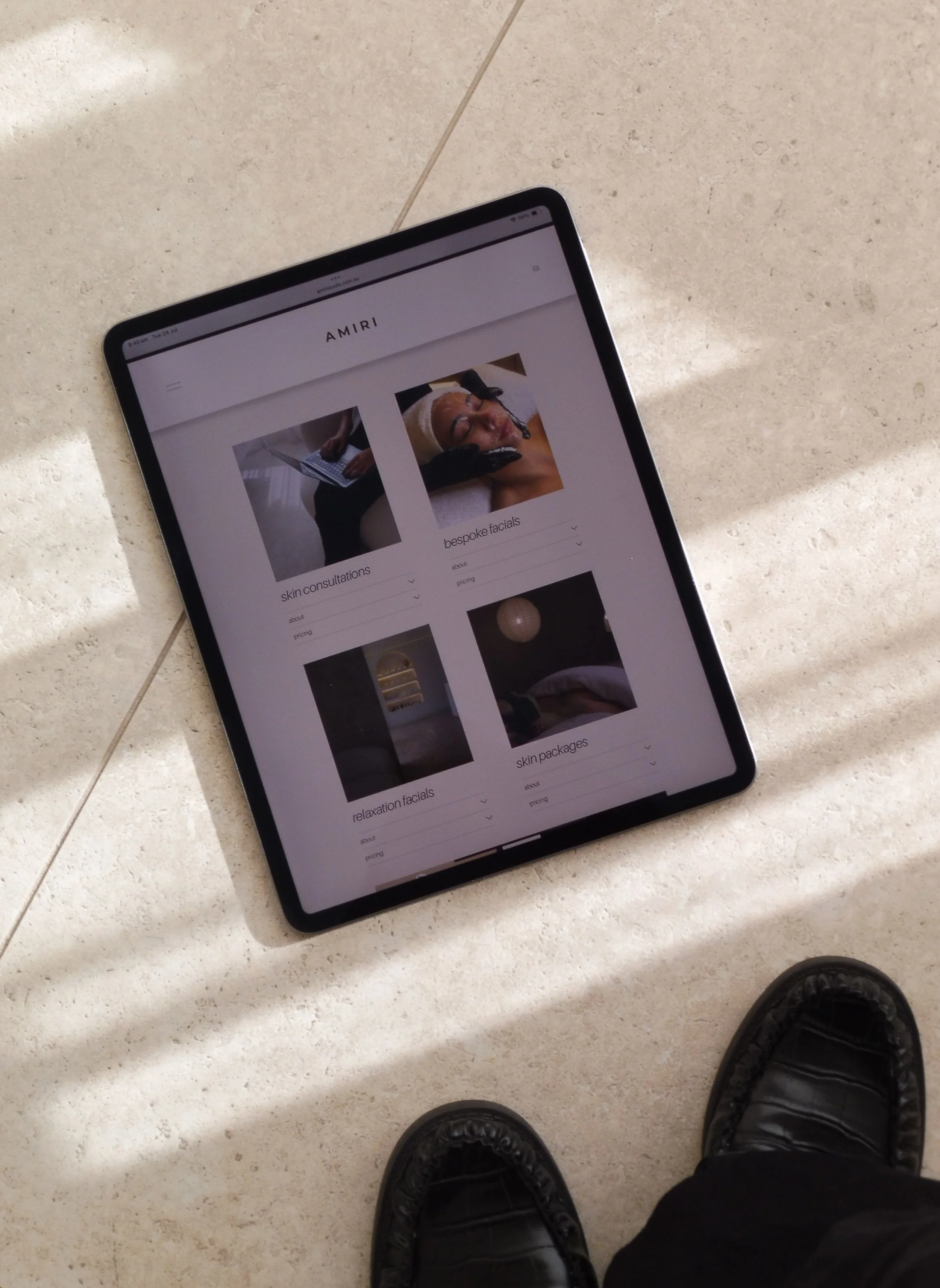 An iPad on the tiles with the AMIRI Studio website treatment page up.