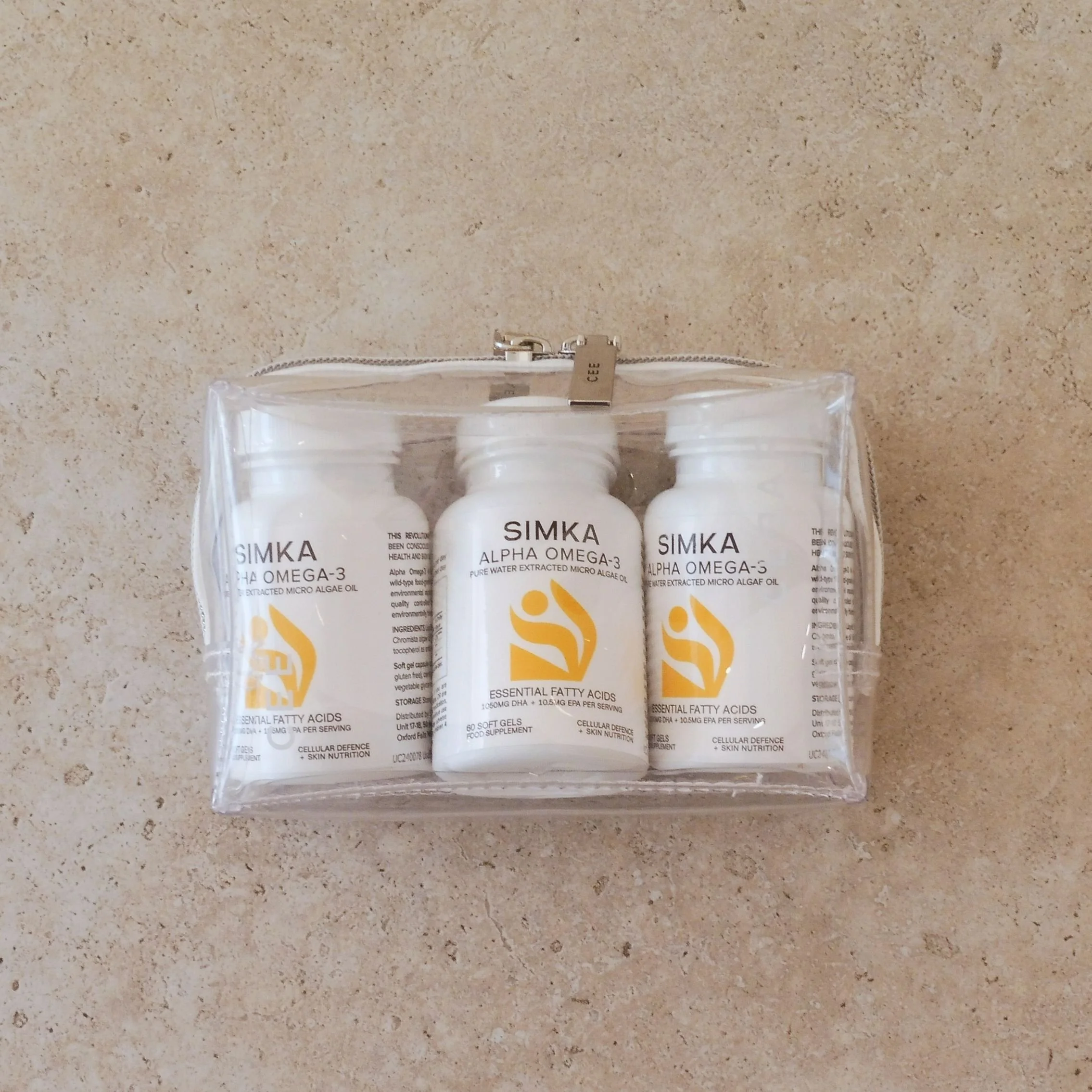 Three bottles of SIMKA Alpha Omega-3 capsules inside a clear zip make up bag at AMIRI Studio Newcastle