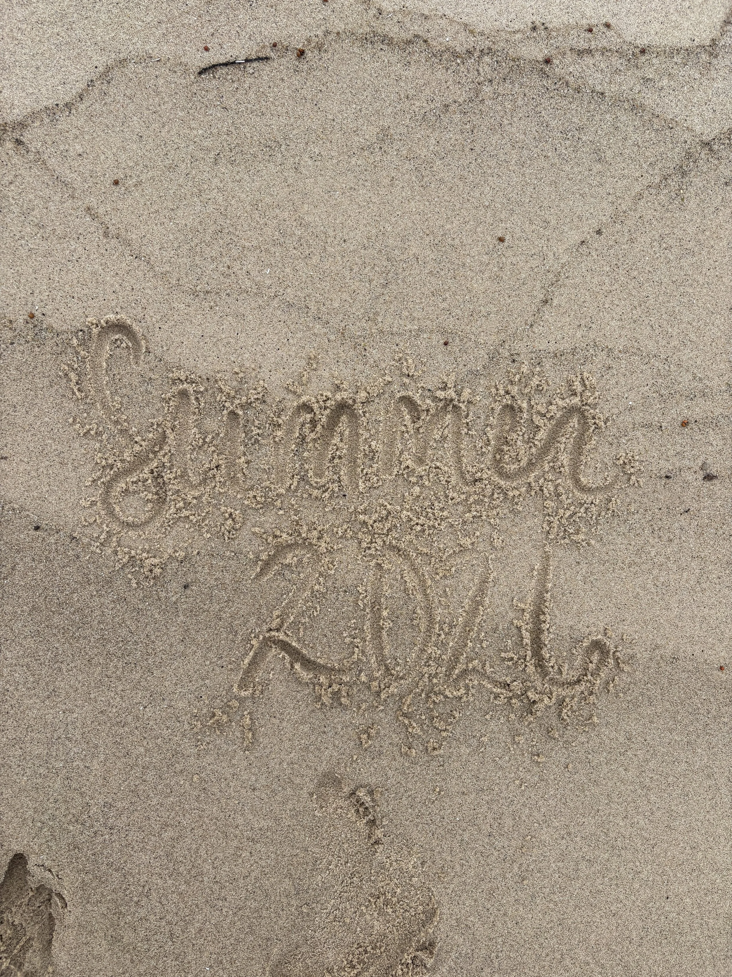 summer 2026 written in beach sand