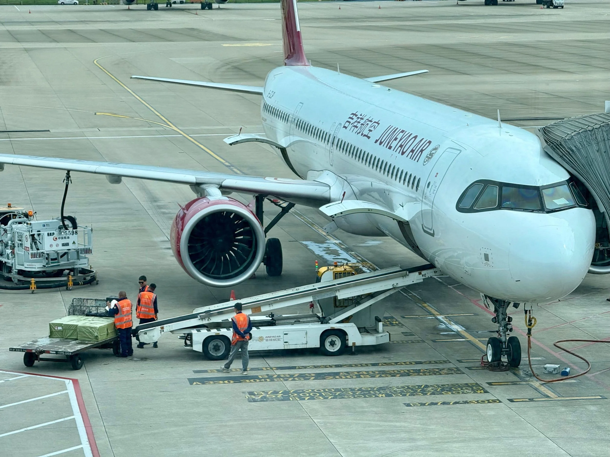 Passengers and ground crew at an airport gate near a plane from China Eastern Airlines, with ground support vehicles and equipment on the tarmac.