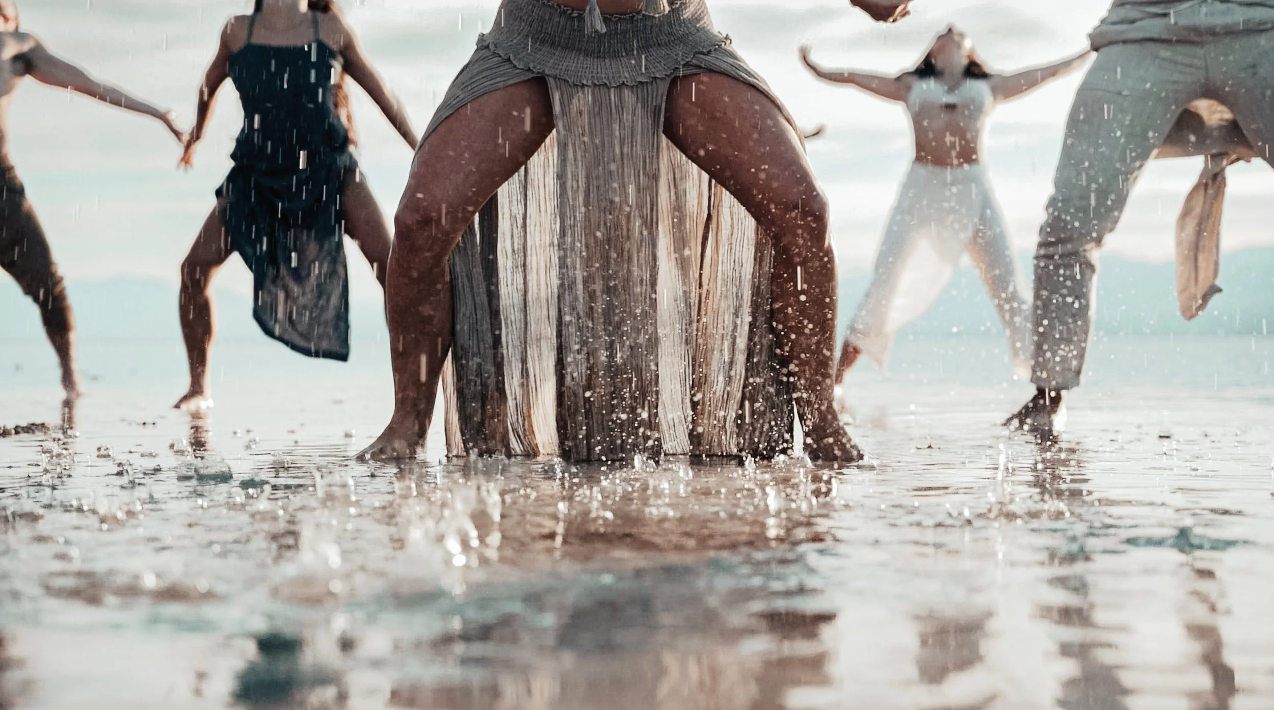KINRGY performers moving together through shallow water.