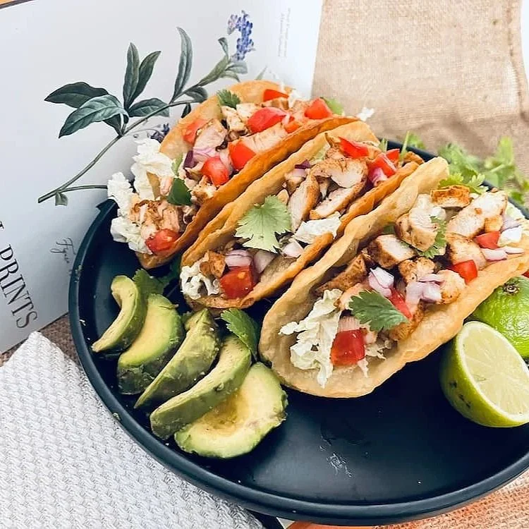 Three chicken tacos seasoned with Hogtown Spice Company taco blend, with sliced avocados and fresh lime wedges.