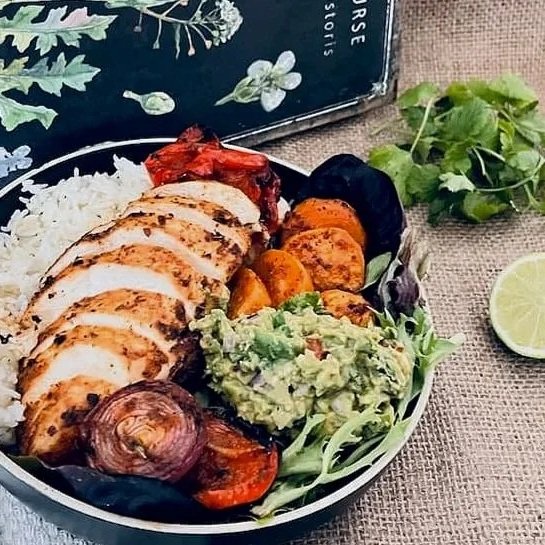 A plated meal featuring grilled chicken breast seasoned with Hogtown Spice Company Taco Seasoning, served with fluffy white rice, creamy guacamole, and charred sweet potato slices.
