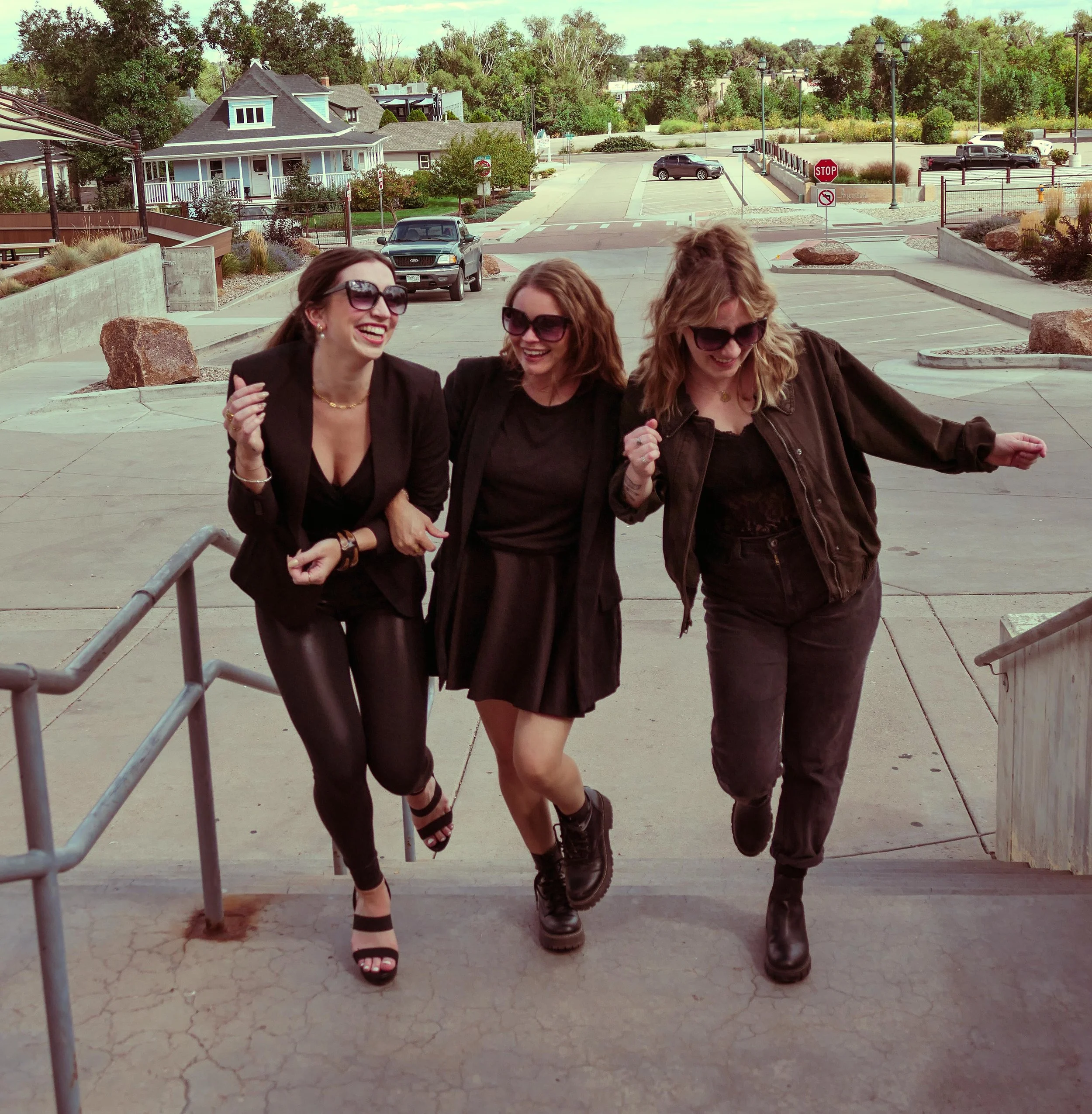 Three professional women laughing and walking up an outdoor staircase.