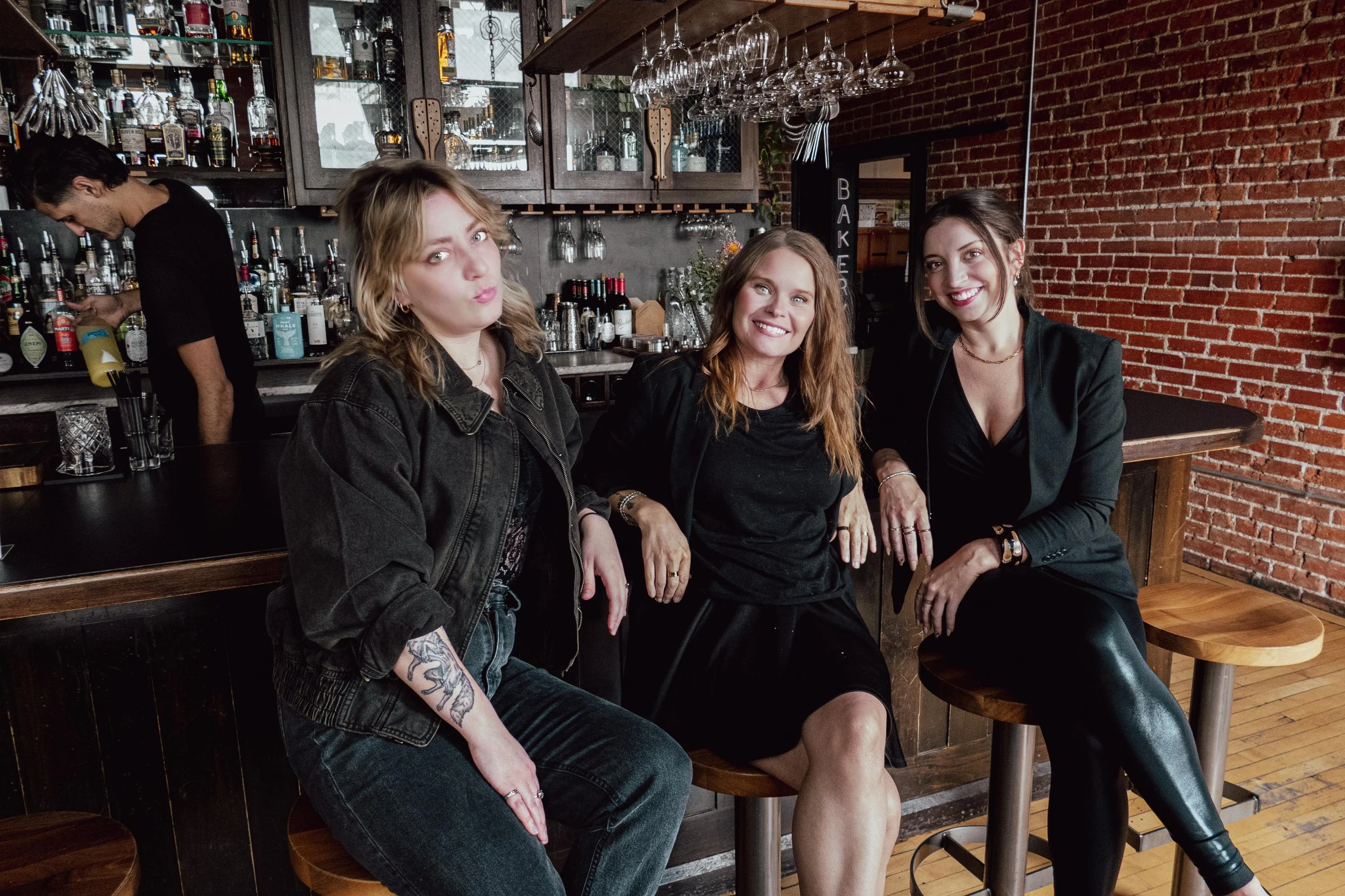 Three professional women in black sitting at a bar