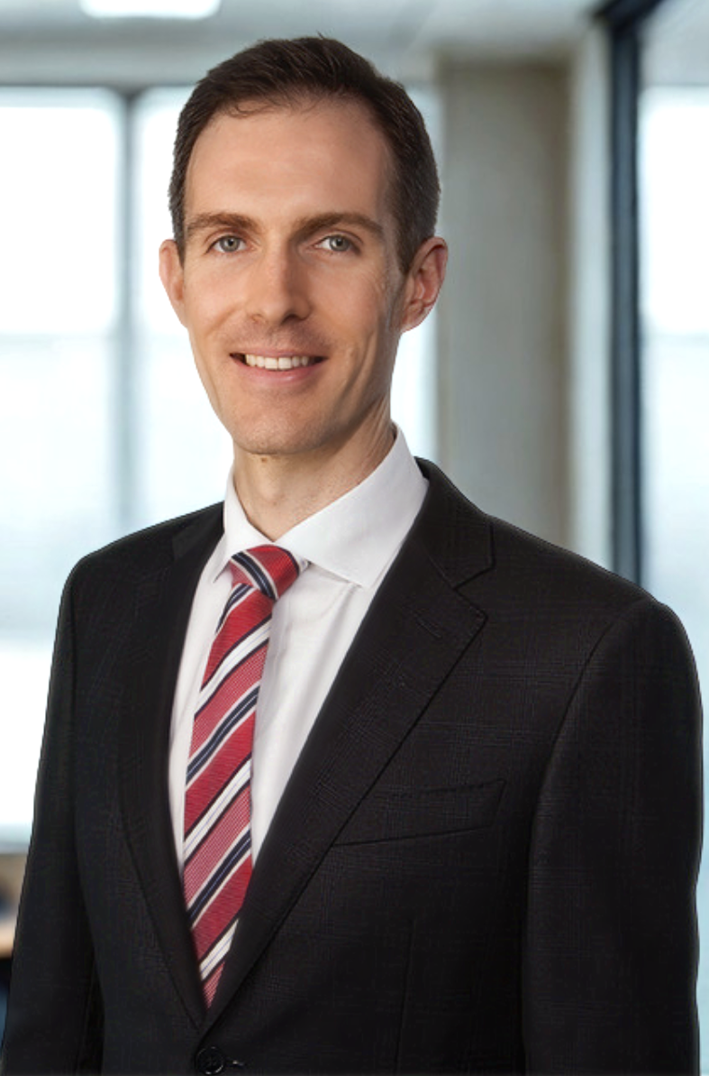 Professional man wearing a black suit, white shirt, and red striped tie, smiling in an office setting.