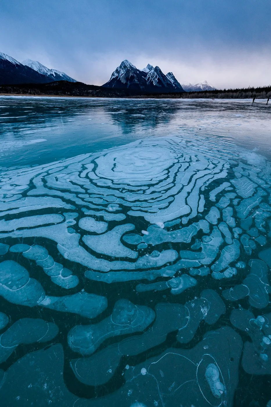 circular ice bubbles with distant mountains frozen lake