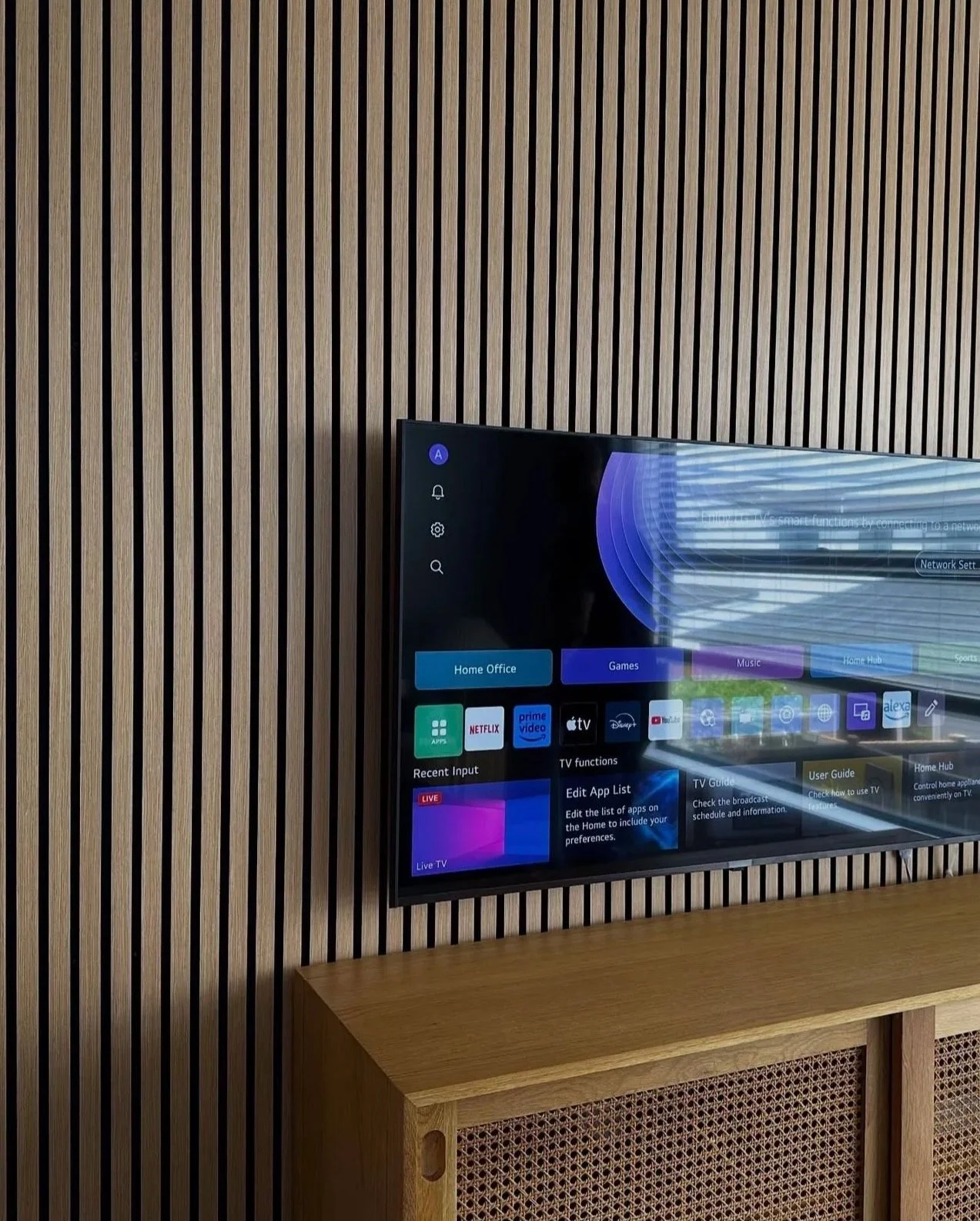 Smart TV mounted on vertical wooden slatted wall, displaying a new smart tv.