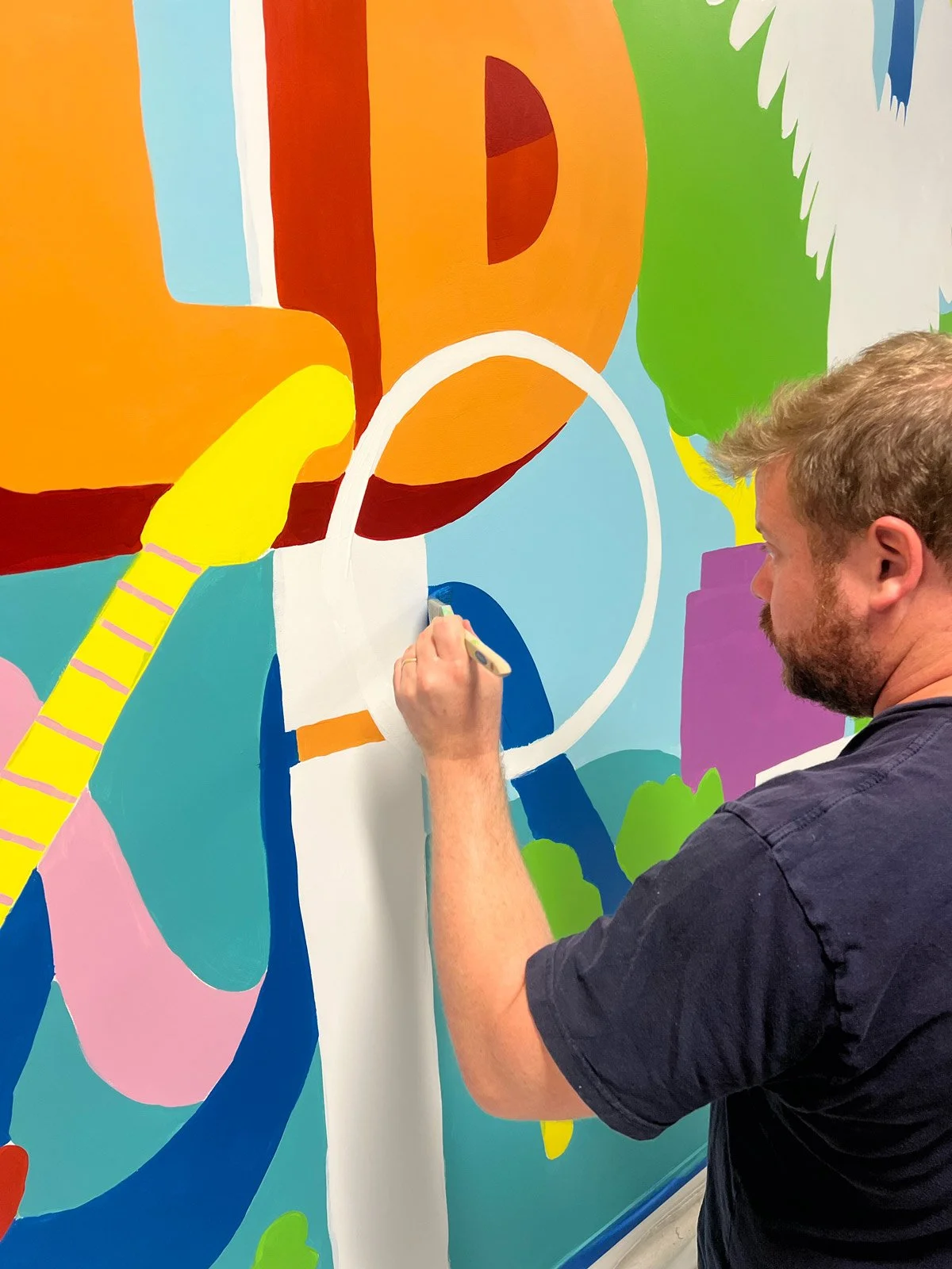 Jimmy Patch painting a bright and colourful mural for Workday.