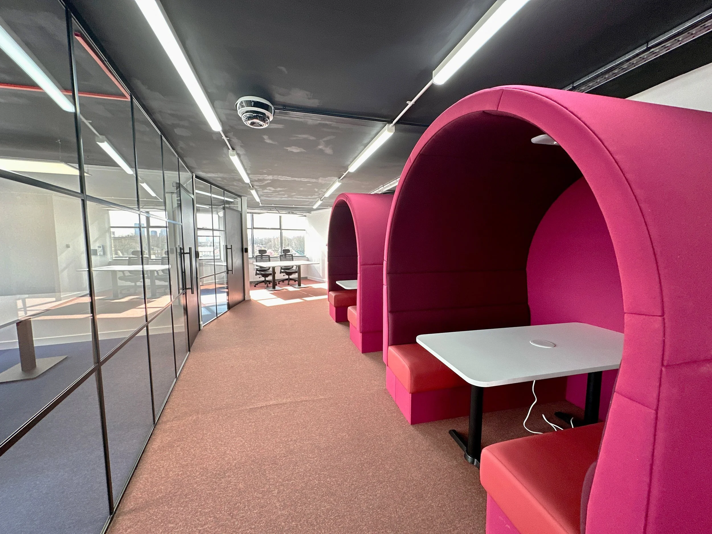 Modern office space with pink pod seating and glass-walled meeting rooms.