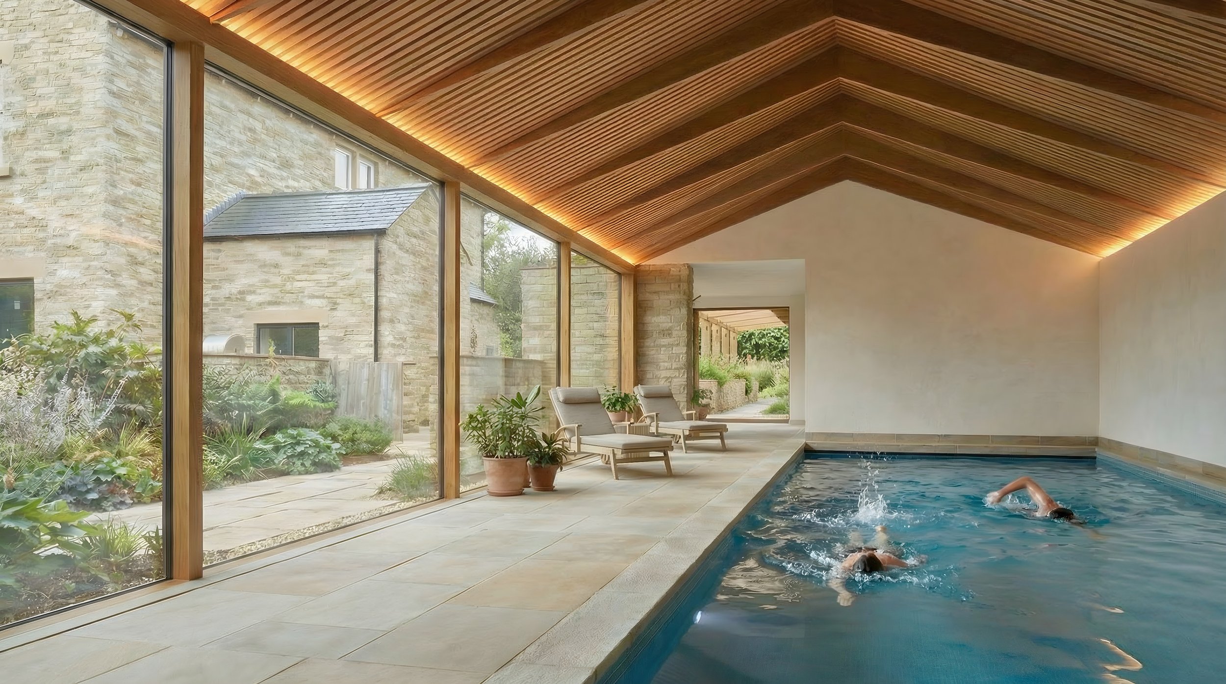 Indoor swimming pool with vaulted cedar ceiling, full-height oak-framed glazing overlooking garden, stone house extension West Yorkshire.