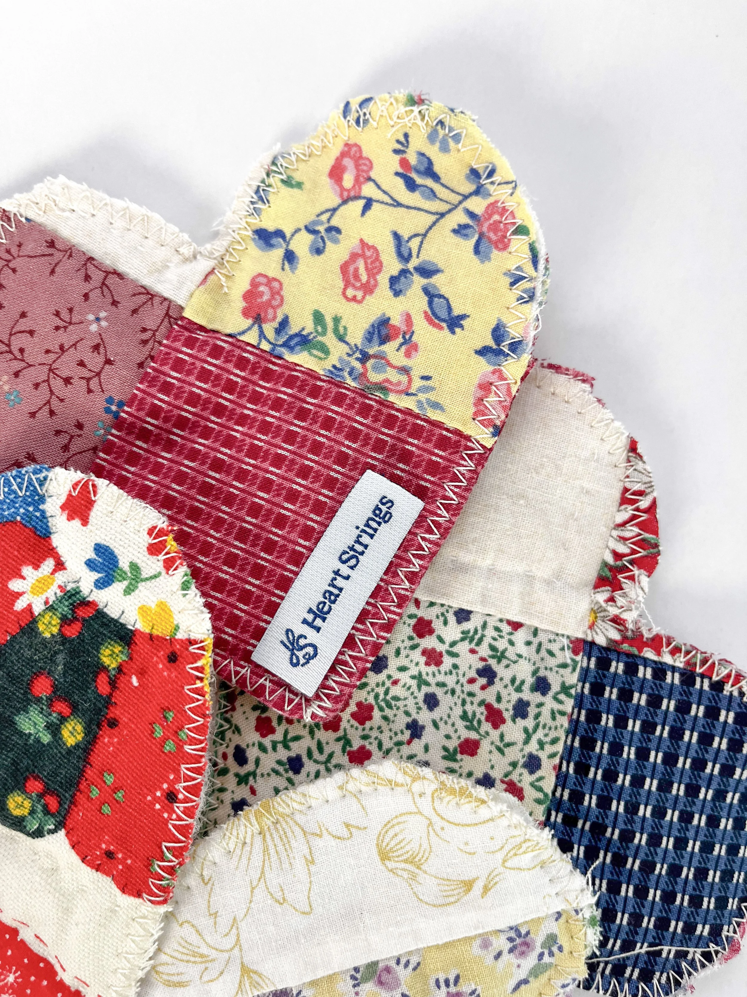 Close-up of colorful fabric heart patches with decorative stitching, one patch has a tag labeled 'Heart Stings'.