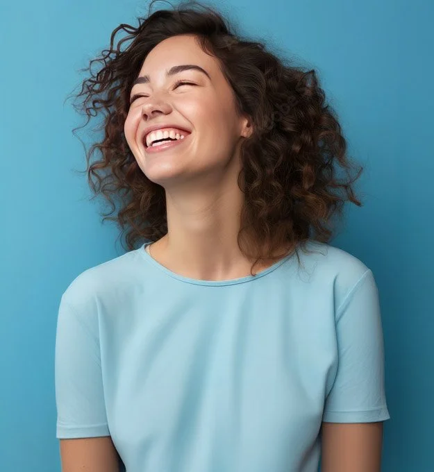 A young woman with curly brown hair, smiling, wearing a light blue shirt.