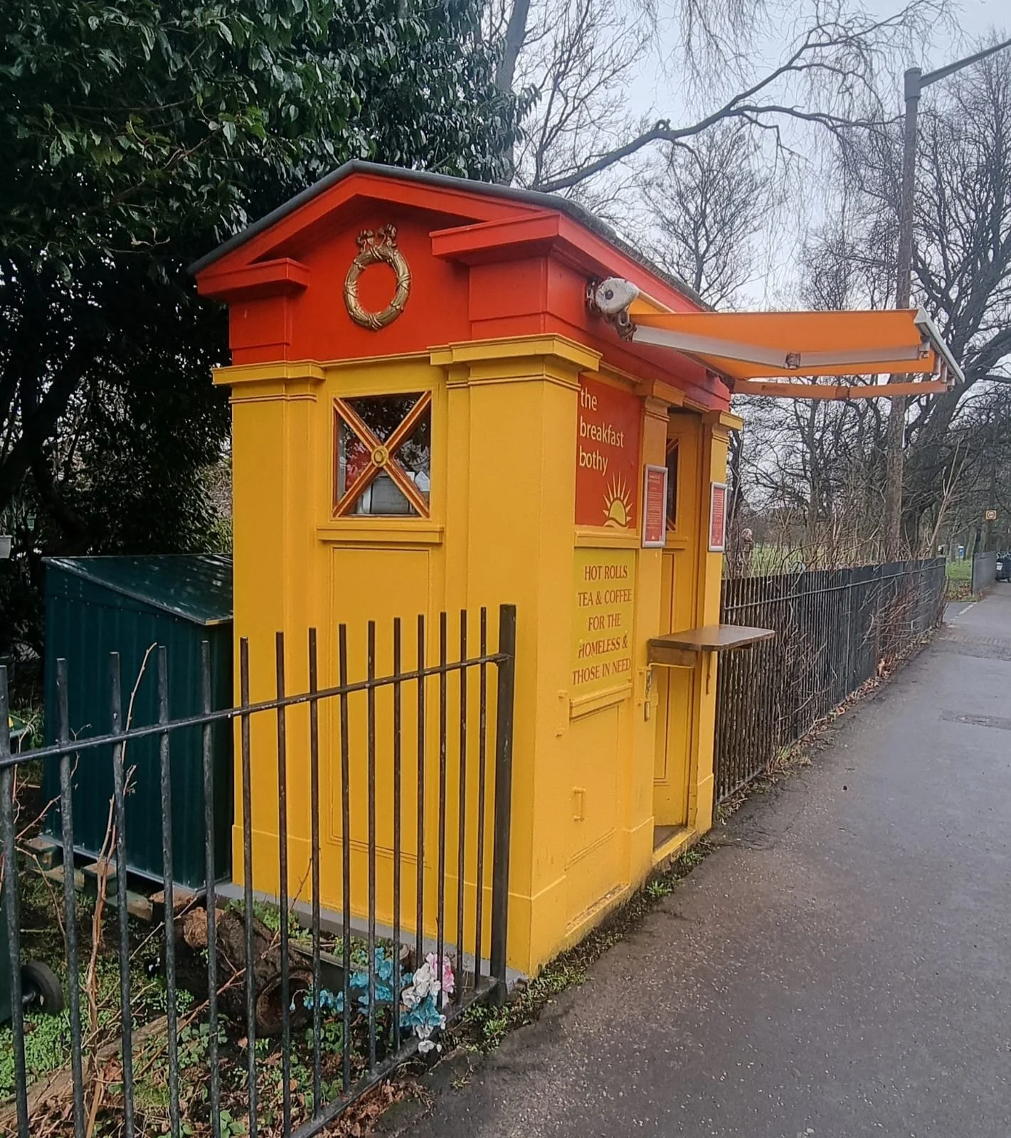 Bright yellow former policebox has an awning open and a new storage box behind