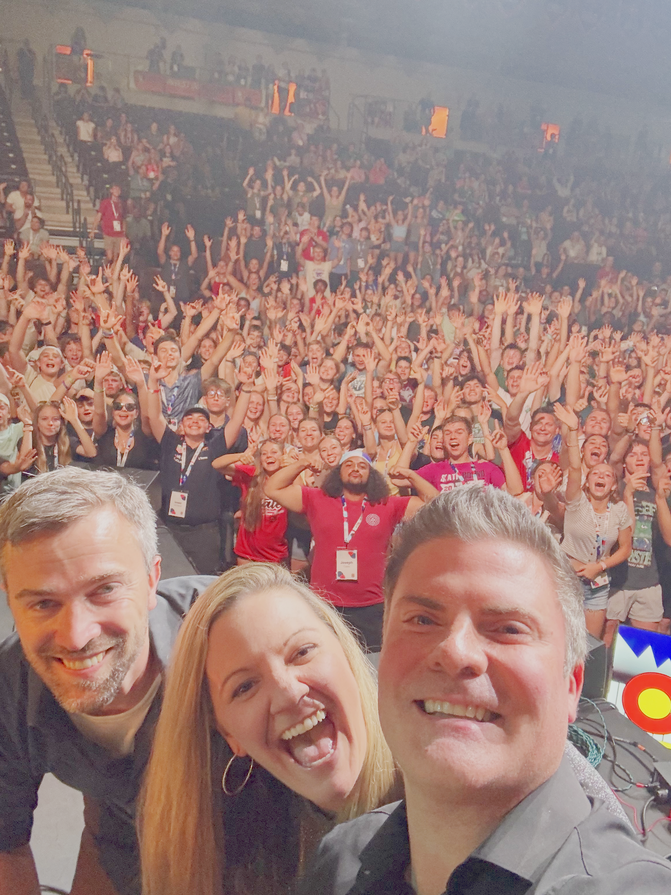 Three musicians taking a selfie in front of a large crowd